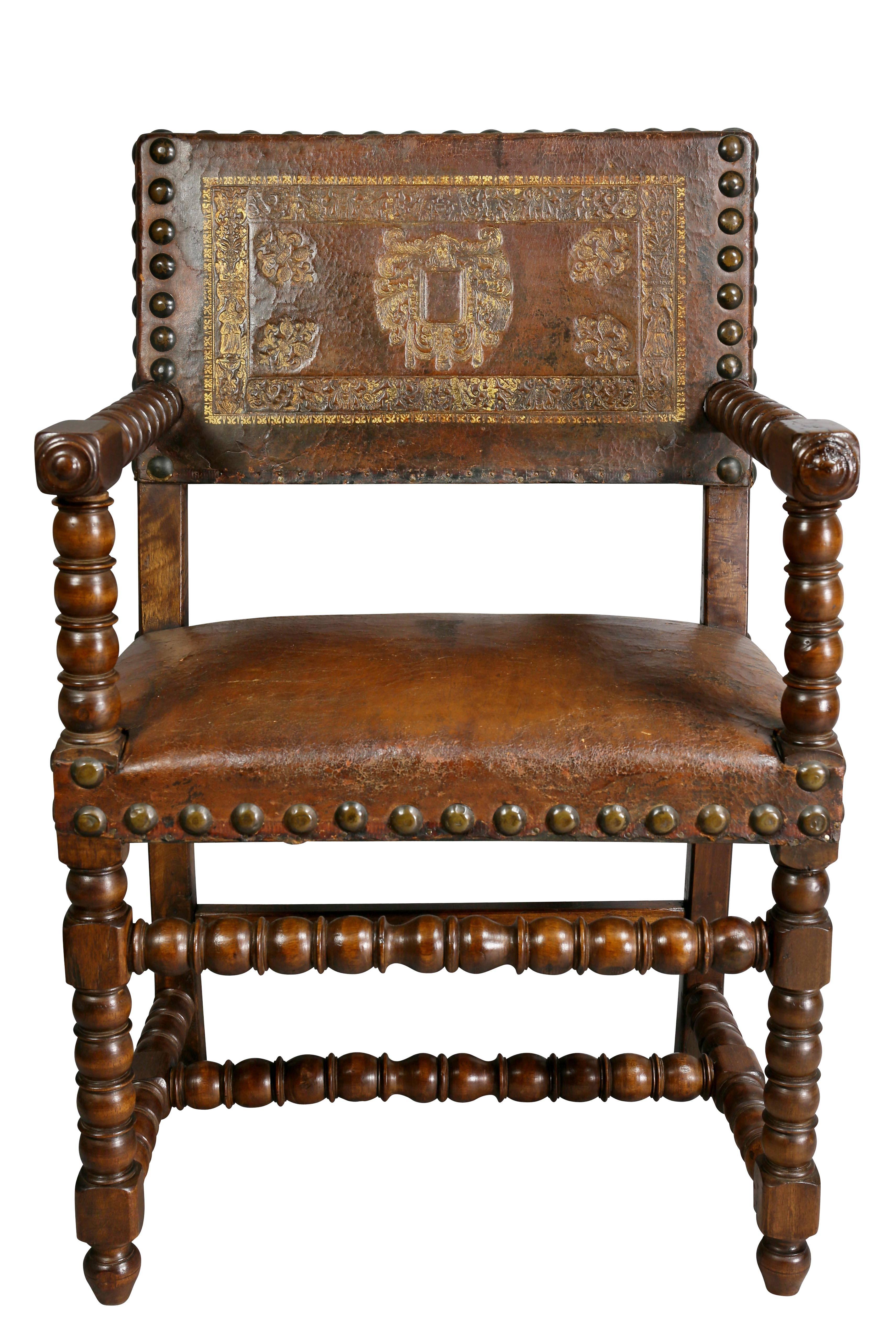 With a rectangular back with embossed leather and brass tacks, turned arms and supports joining a leather seat, raised on turned legs with stretchers, toupie feet. Provenance; Fogg Estate.