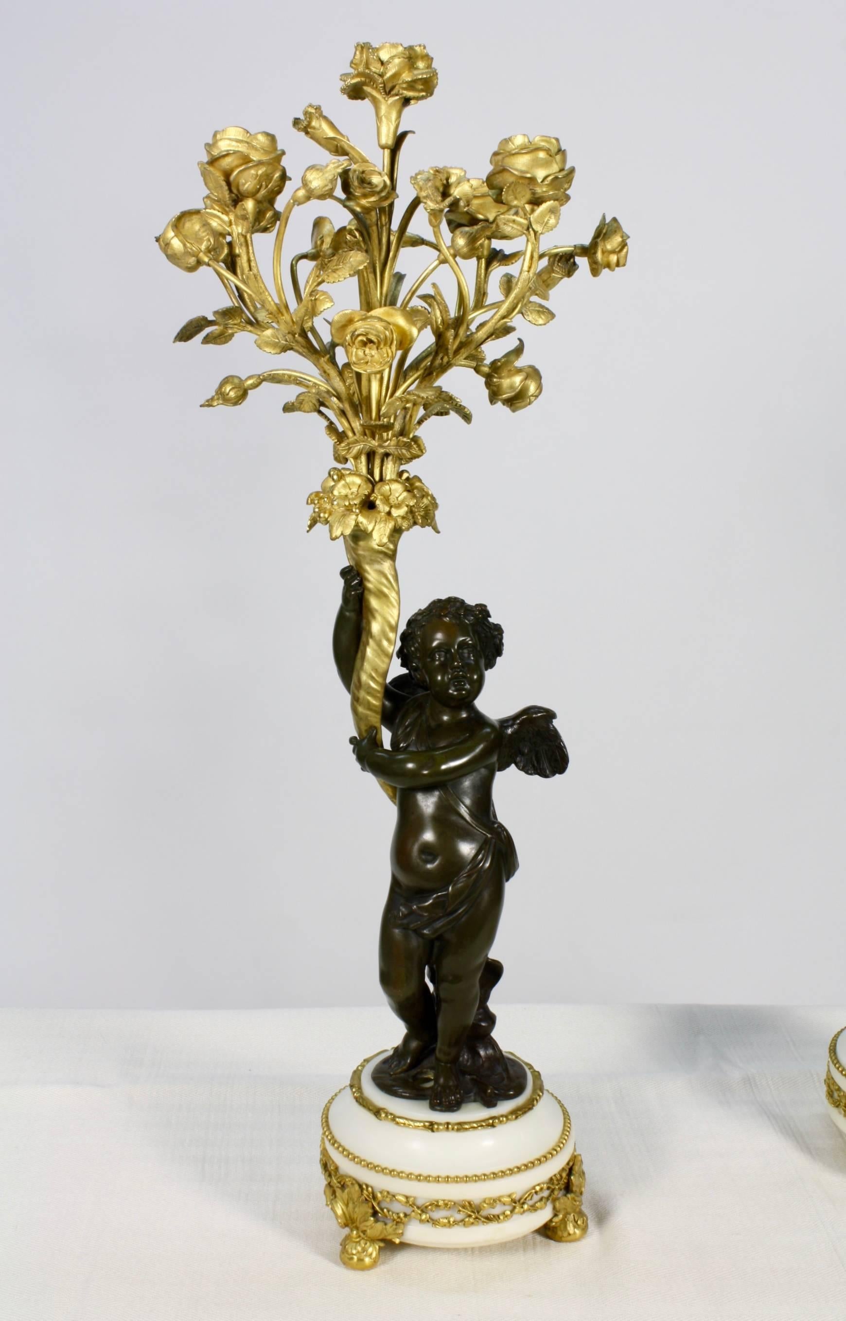Doré Paire de candélabres en bronze doré et patiné avec putti tenant des bouquets de fleurs en vente
