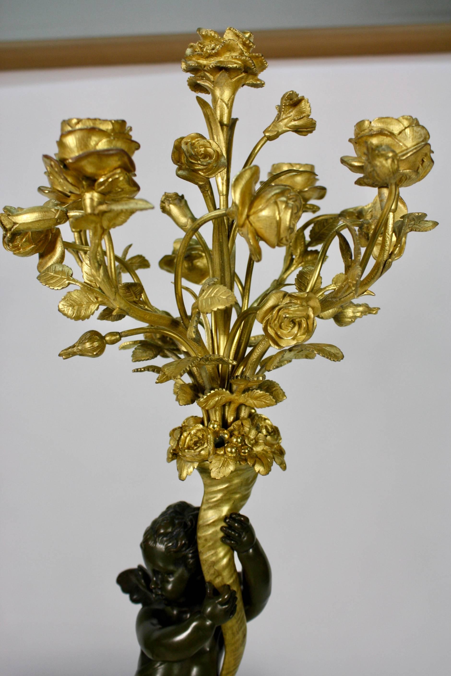 Bronze Paire de candélabres en bronze doré et patiné avec putti tenant des bouquets de fleurs en vente