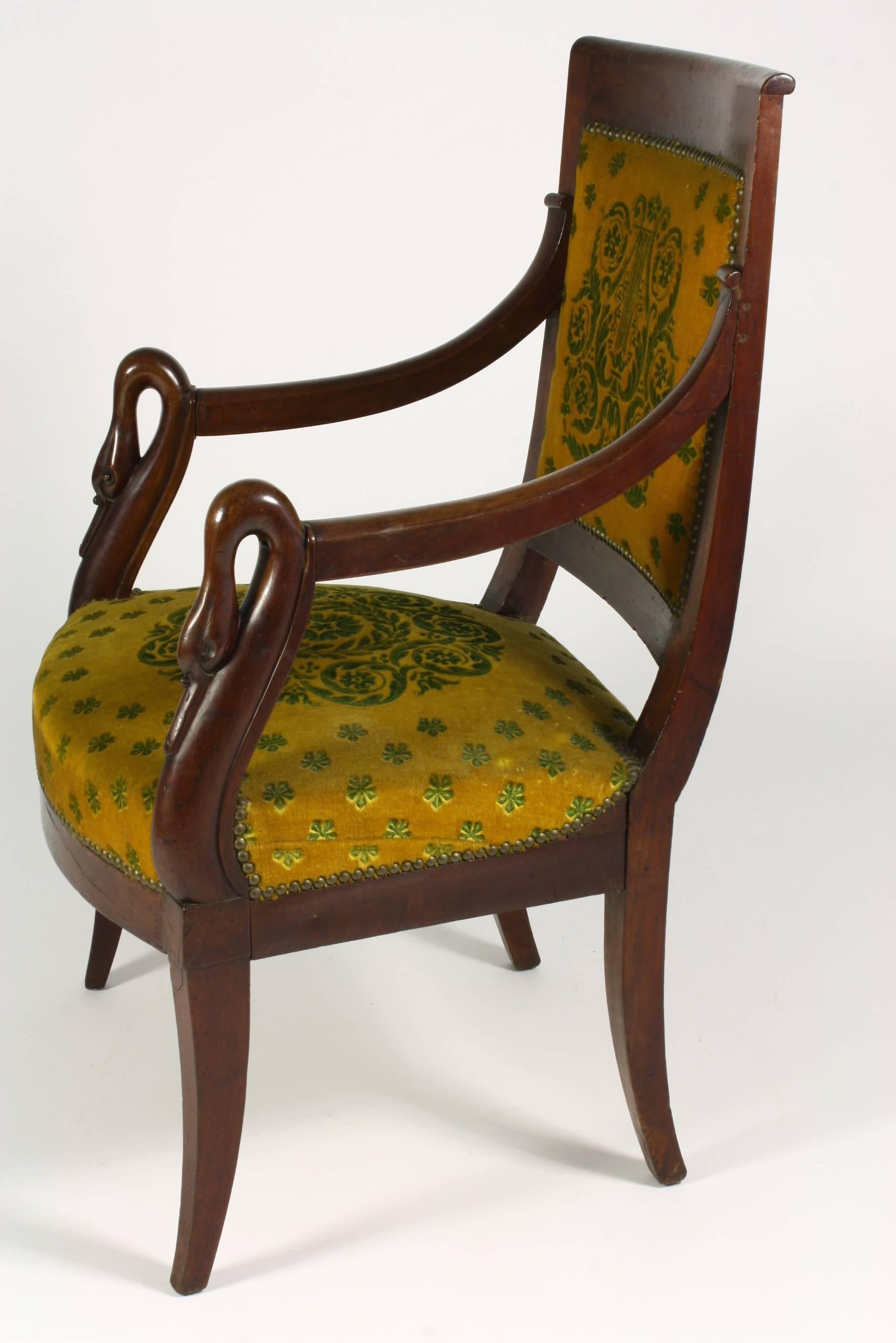 Französischer Fauteuil oder Sessel aus Mahagoni der Empirezeit mit Säbelbeinen und Schwanenköpfen an den Armlehnen.  Der Stuhl ist mit neoklassisch gemustertem Mohair-Stoff gepolstert.