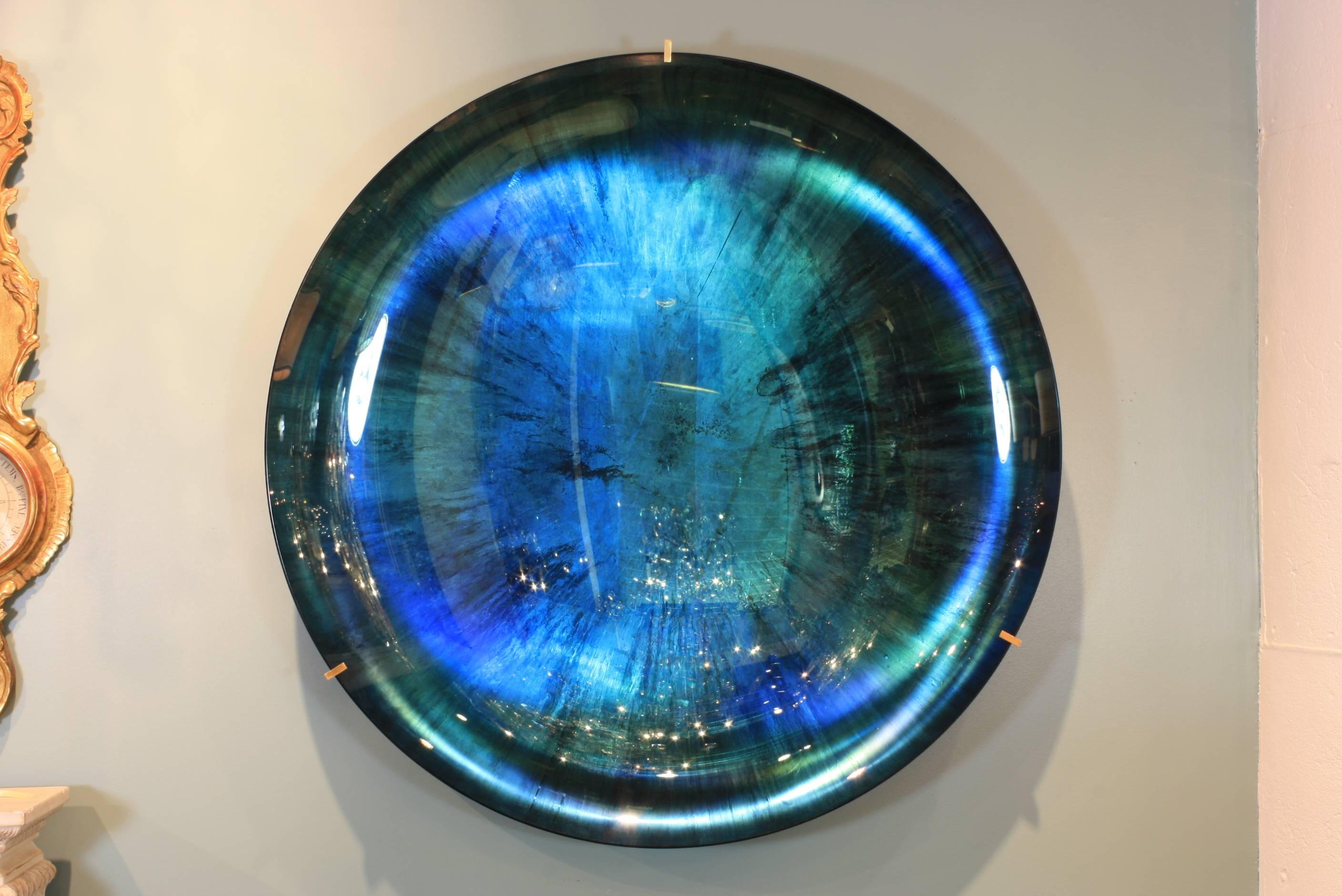 Large blue-green-teal concave art glass mirror with custom-made brass bracket. This French mirror is a unique, hand-made piece of wall art. The bracket is signed by the artist, Christophe Gaignon, Paris 2015.  A very similar mirror, made by Mr.