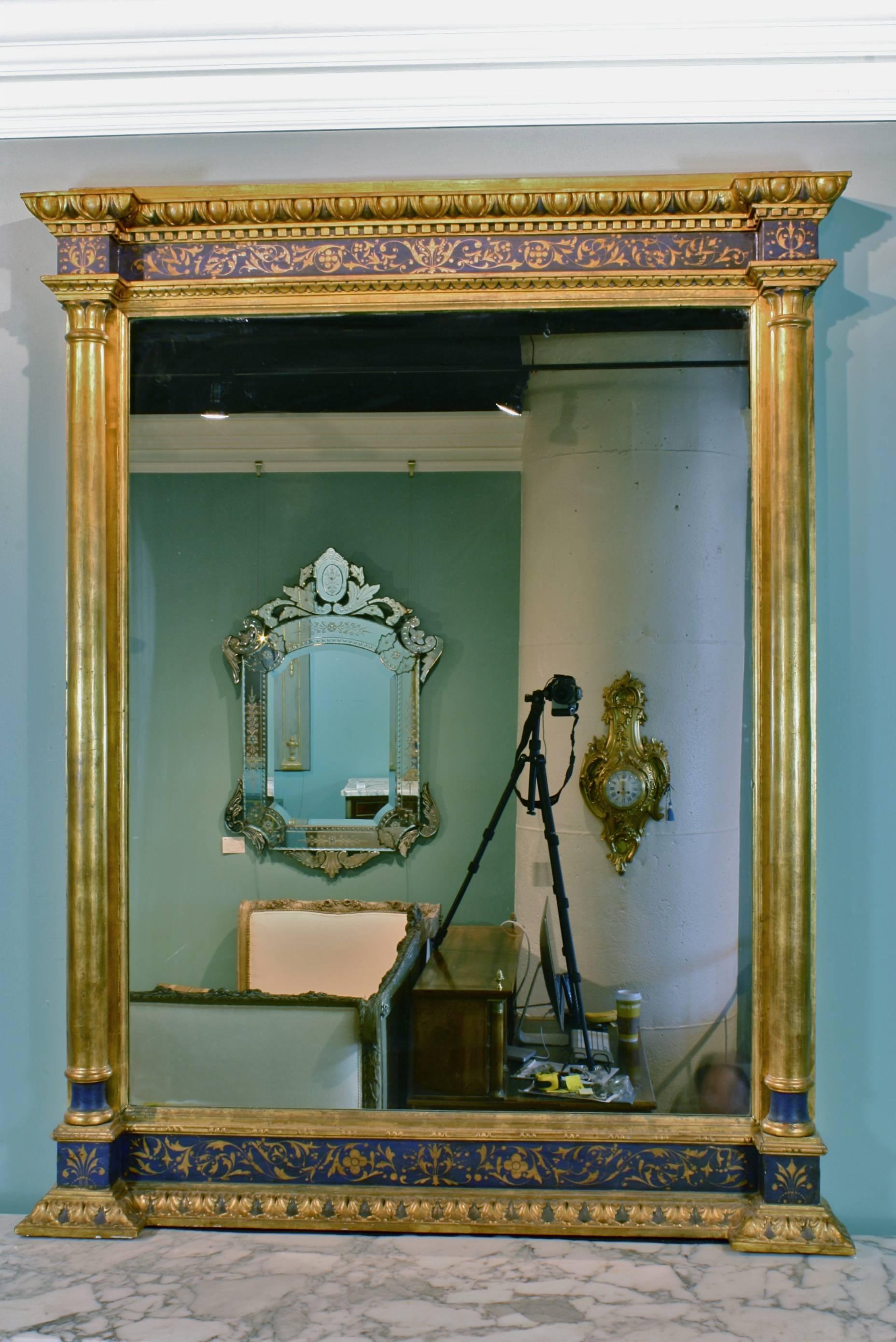 Un grand et inhabituel miroir français en bois peint en bleu et doré, avec des détails en bois doré finement décorés, des colonnes en bois doré détachées, et une garniture en forme d'œuf et de fléchette.