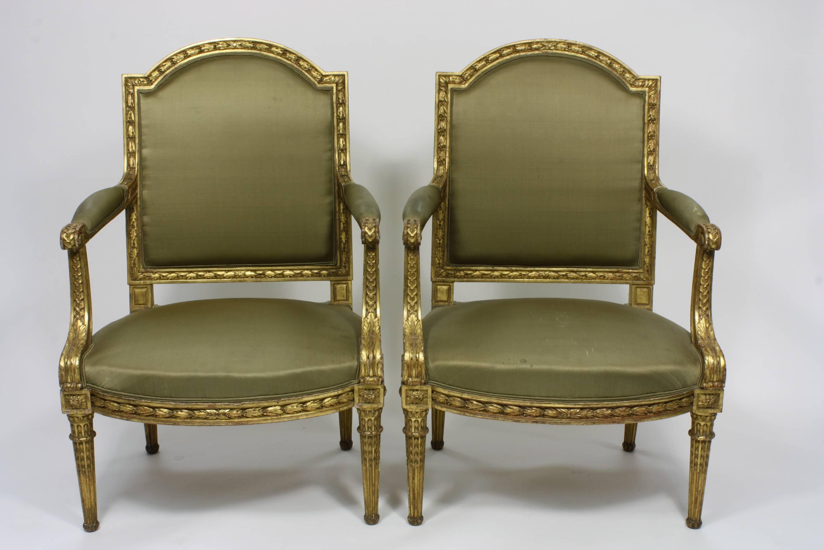 An elegant pair of 19th century French Louis XVI style giltwood armchairs or fauteuils. Nicely-carved guilloche patterning on the arms, terminating in scrolls with acanthus leaves. The backs and front seat rails are decorated with carved laurel