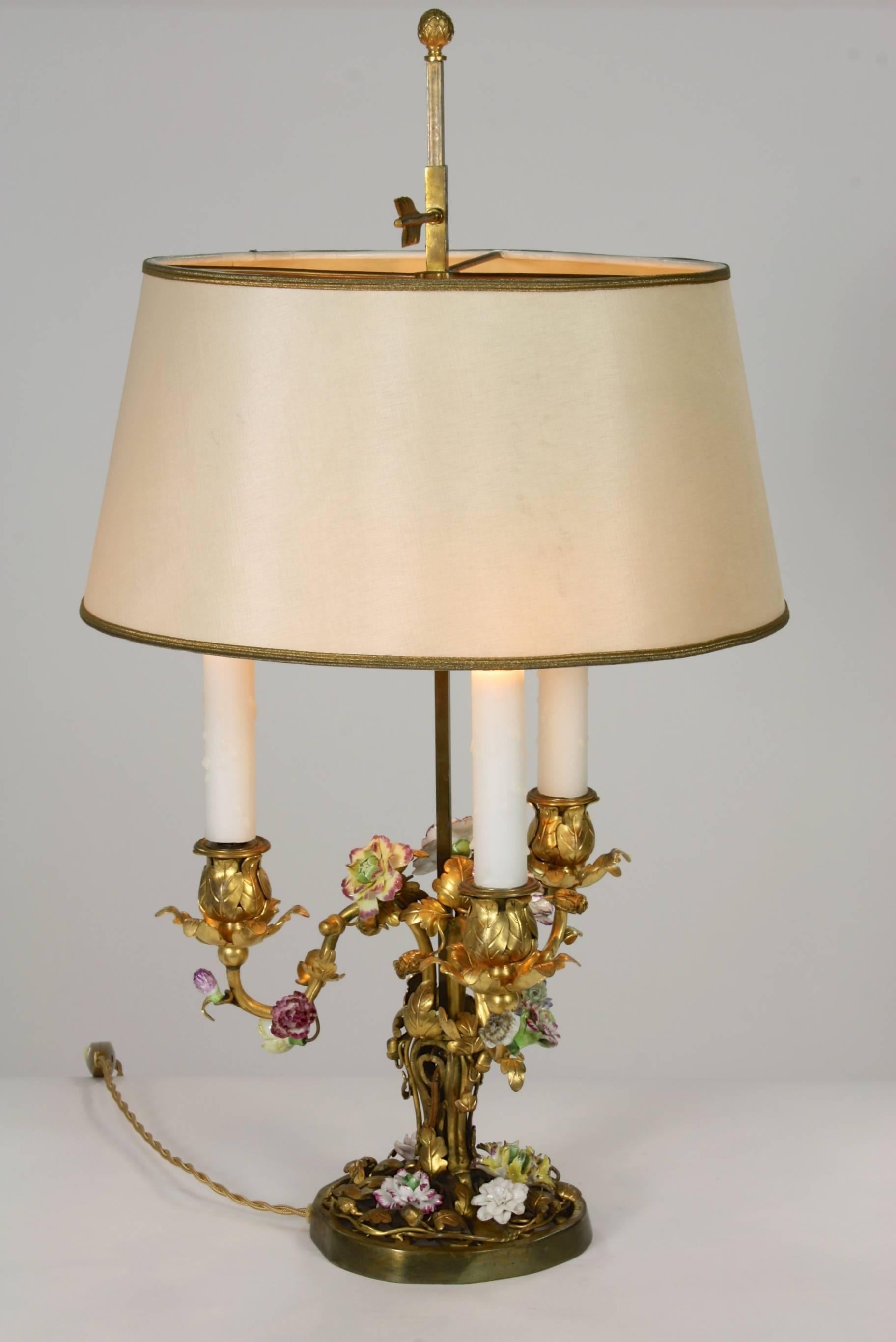 A very fine, 19th century French gilt bronze Louis XV style bouillotte lamp, in foliate form with multicolored porcelain flowers, electrified with three lights. Silk over paper adjustable shade. Napoleon III period.