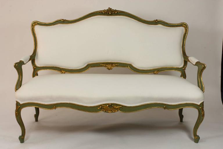 A very stylish Italian green and gold polychromed settee in the Rococo style, recently re-upholstered in muslin.