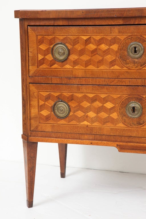 This beautiful walnut chest features two drawers, exquisite marquetry detail throughout body and on top and bronze hardware. The piece, with chamfered corners, is raised on tapered legs.