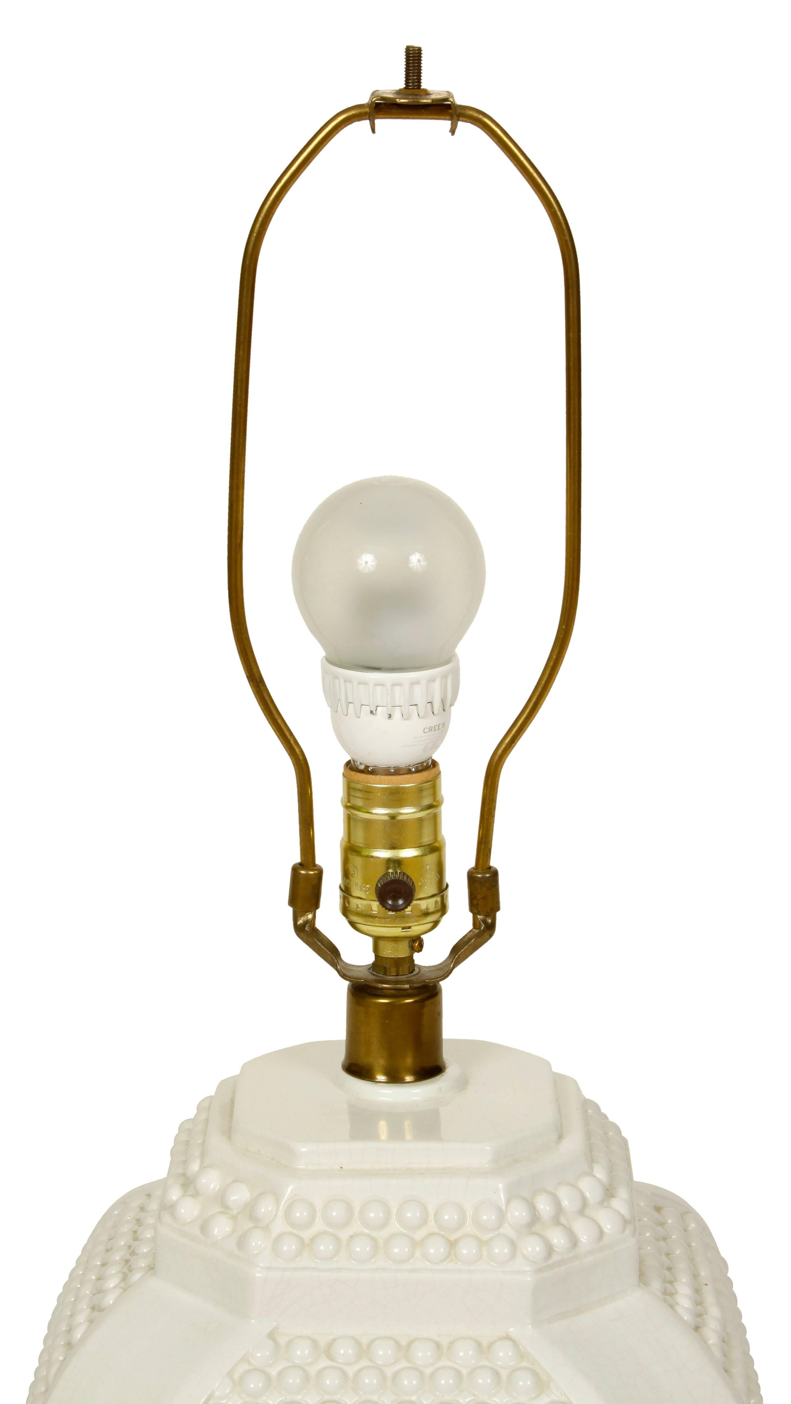 A unique and versatile pair of white ceramic lamps with a raised "dot" pattern and a octagonal shaped brass base with black shades.