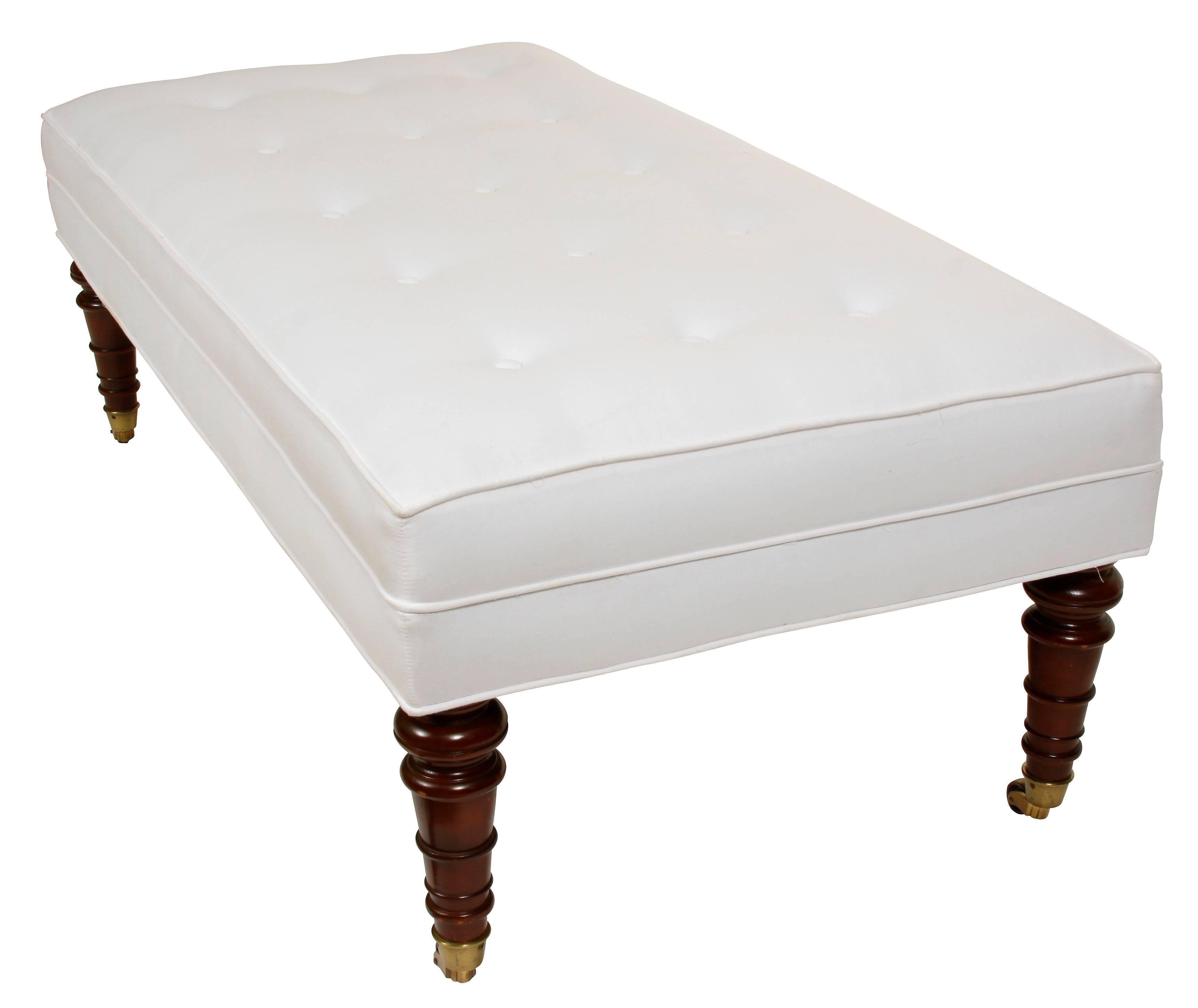 We love this ottoman for its scale and simple lines. Tailored and clean, this versatile piece features button tufting on top with welting on outer edge and on sides. The turned mahogany legs are on brass casters. Perfect for extra seating, or a as a