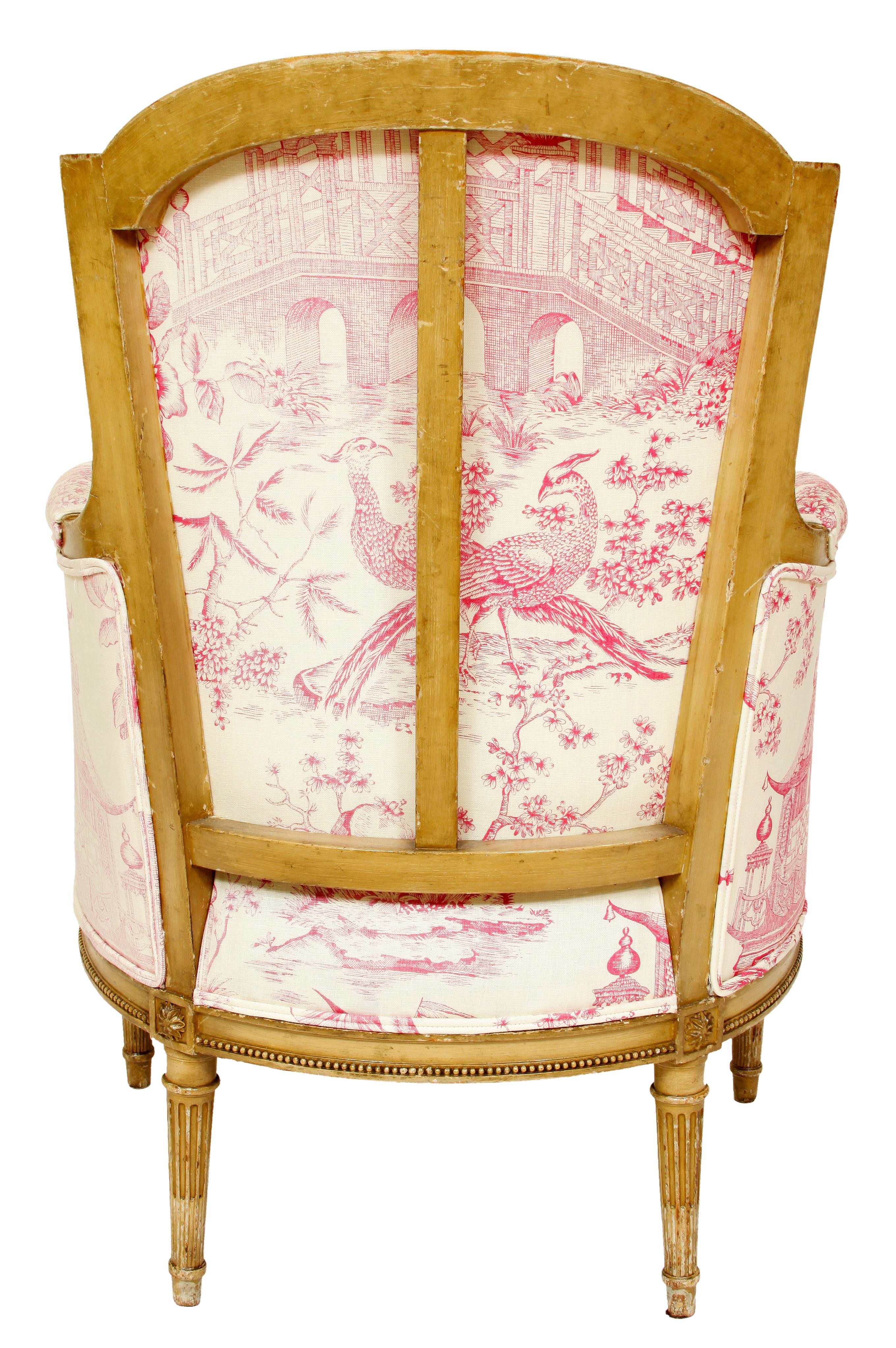 A charming trio of two French bergere chairs and an ottoman. The set features the elegant, yet understated details characteristic of the Louis XVI style--a slightly curved tight back, detailed carving on arm supports and die joins, and fluted,