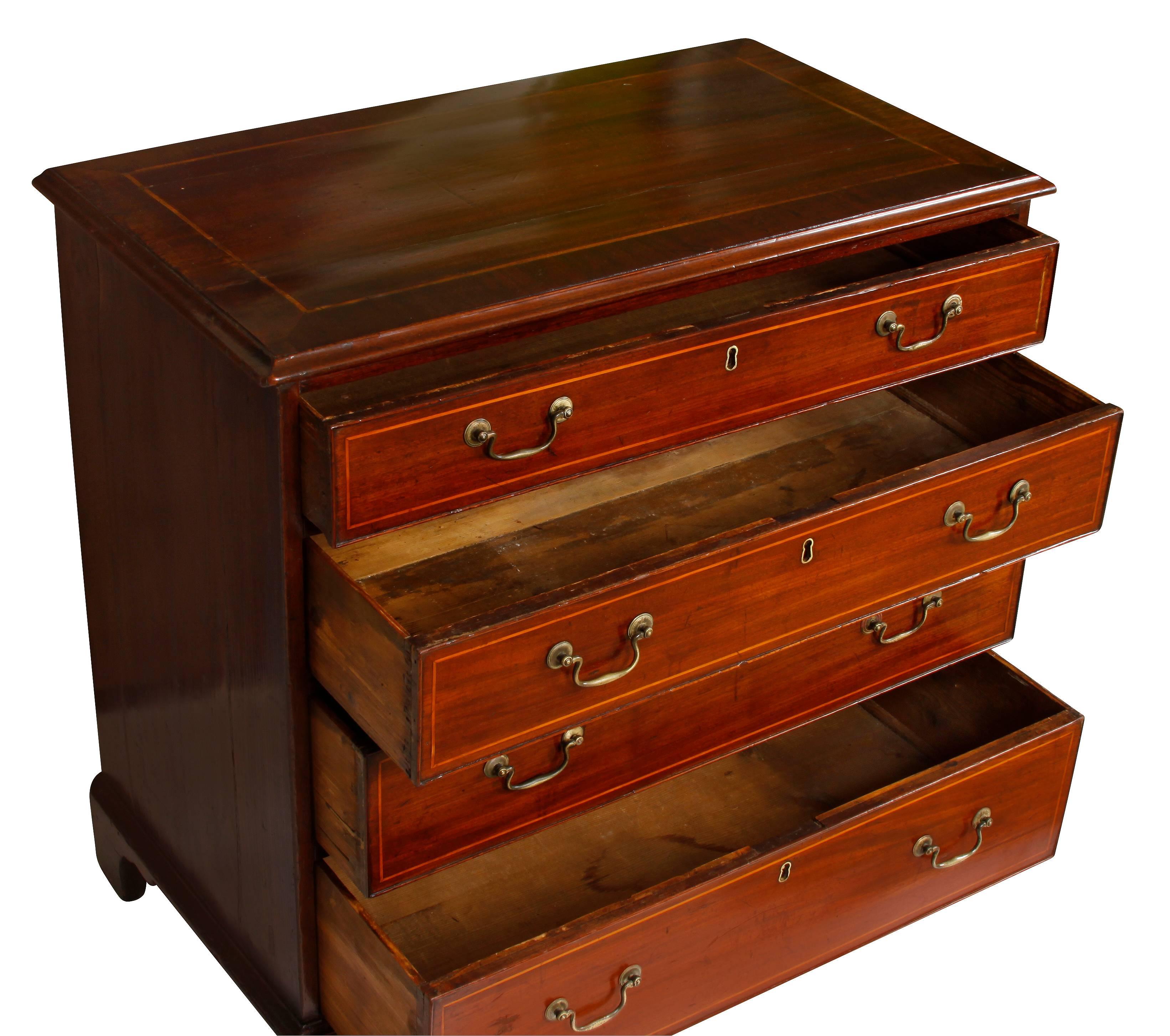 A lovely little English mahogany chest that could be freestanding, or serve as an end table or bedside table. The piece features four graduated drawers with original hardware, with simple inlaid design on top and on drawer fronts; raised on bracket