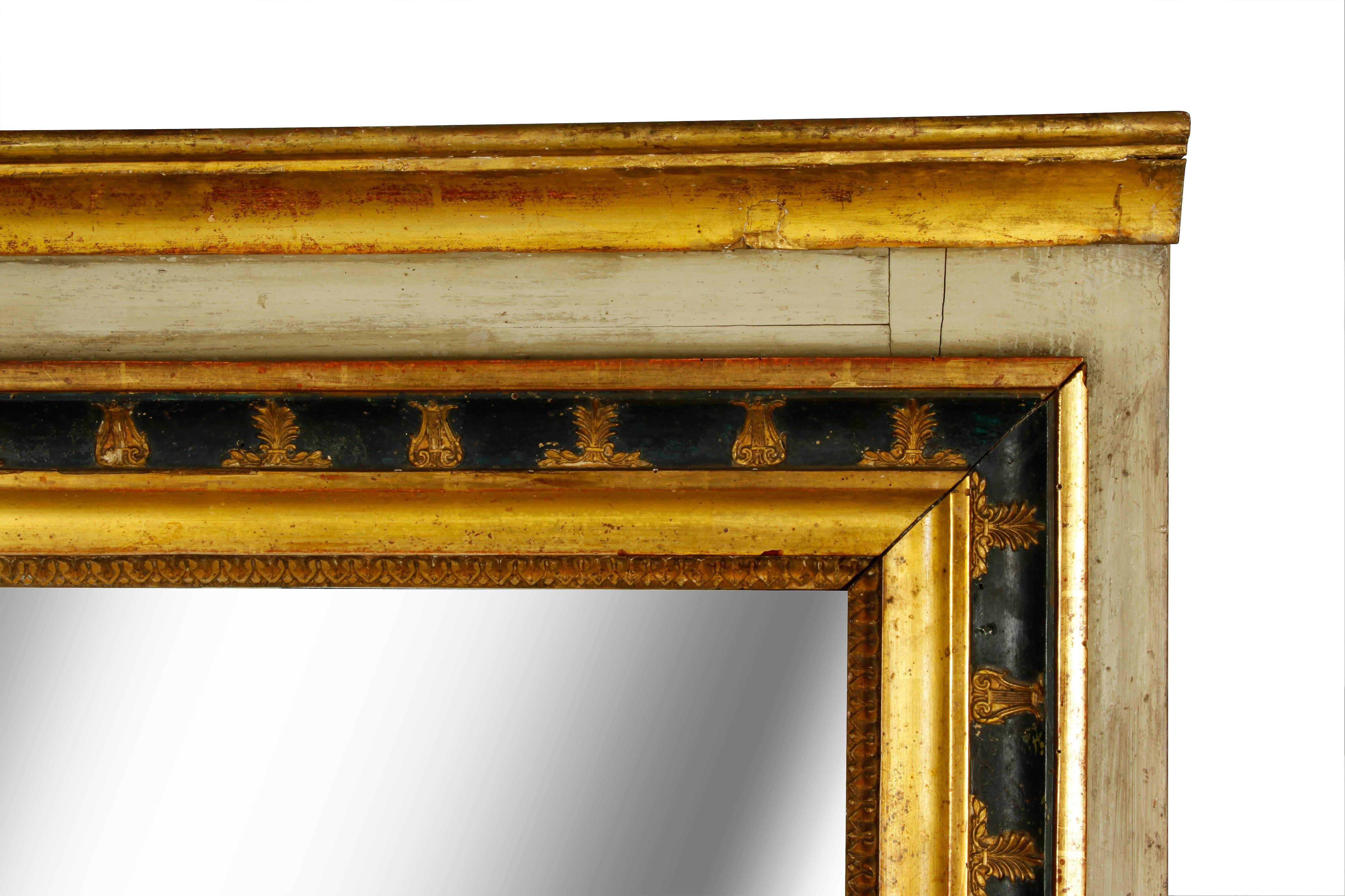 This large painted and parcel-gilt Italian mirror exudes character. The giltwood frame, carved with decorative elements, encloses the glass in two plates. The border, painted black and a gray/green, has faded to a lovely soft patina. A real gem!