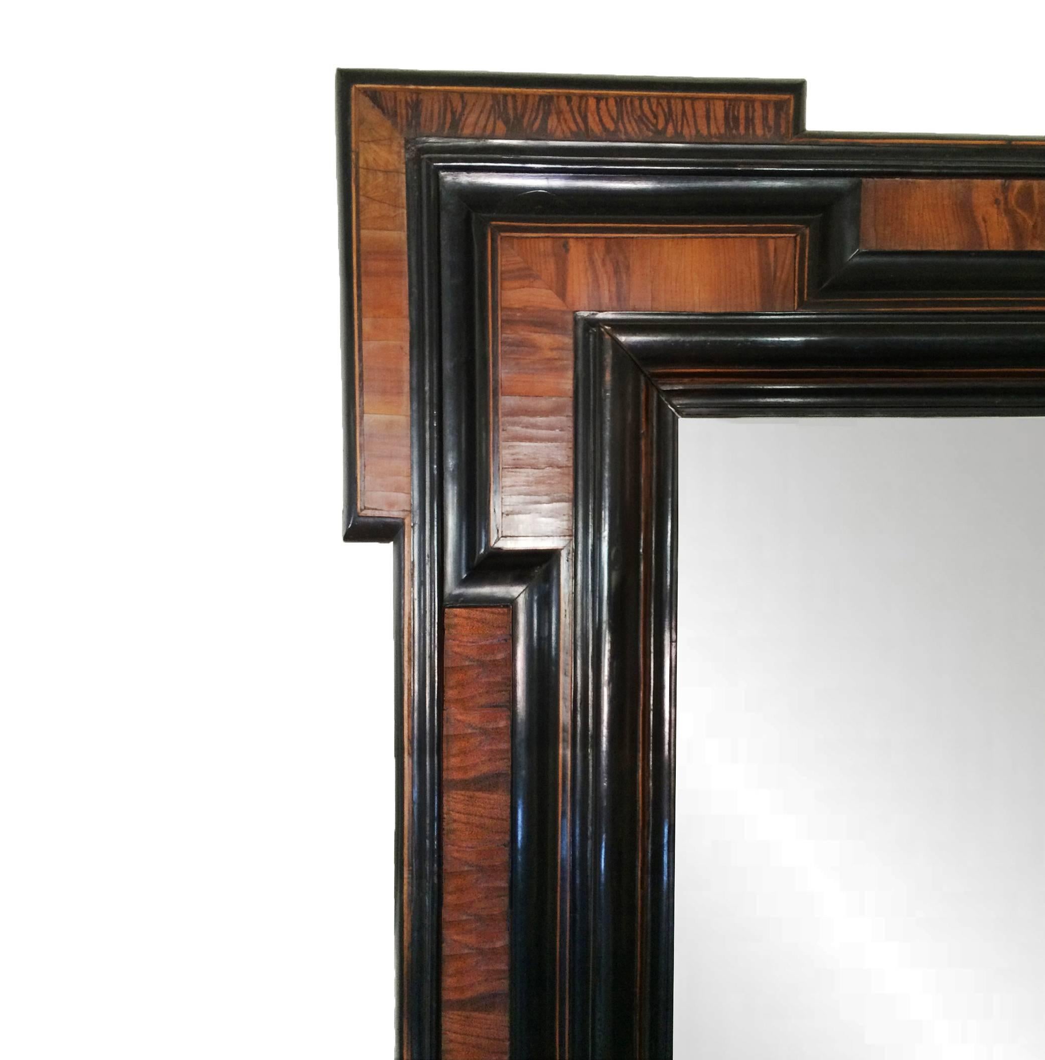 Italian Piemontese Baroque mirror; having stepped corners and multiple layers of walnut veneer within ebonized moldings; 18th Century.