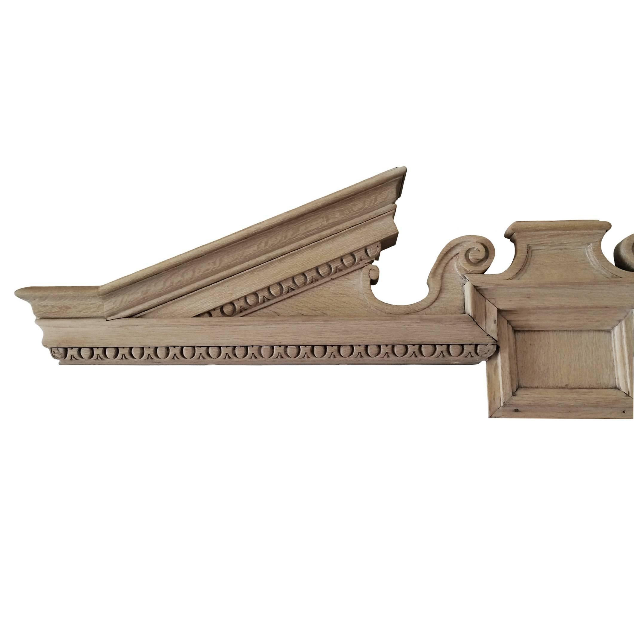 Pair of French Neoclassical architectural limed oak overdoor pediments, intricately carved sculptural details, 19th century.  Sold as a pair.