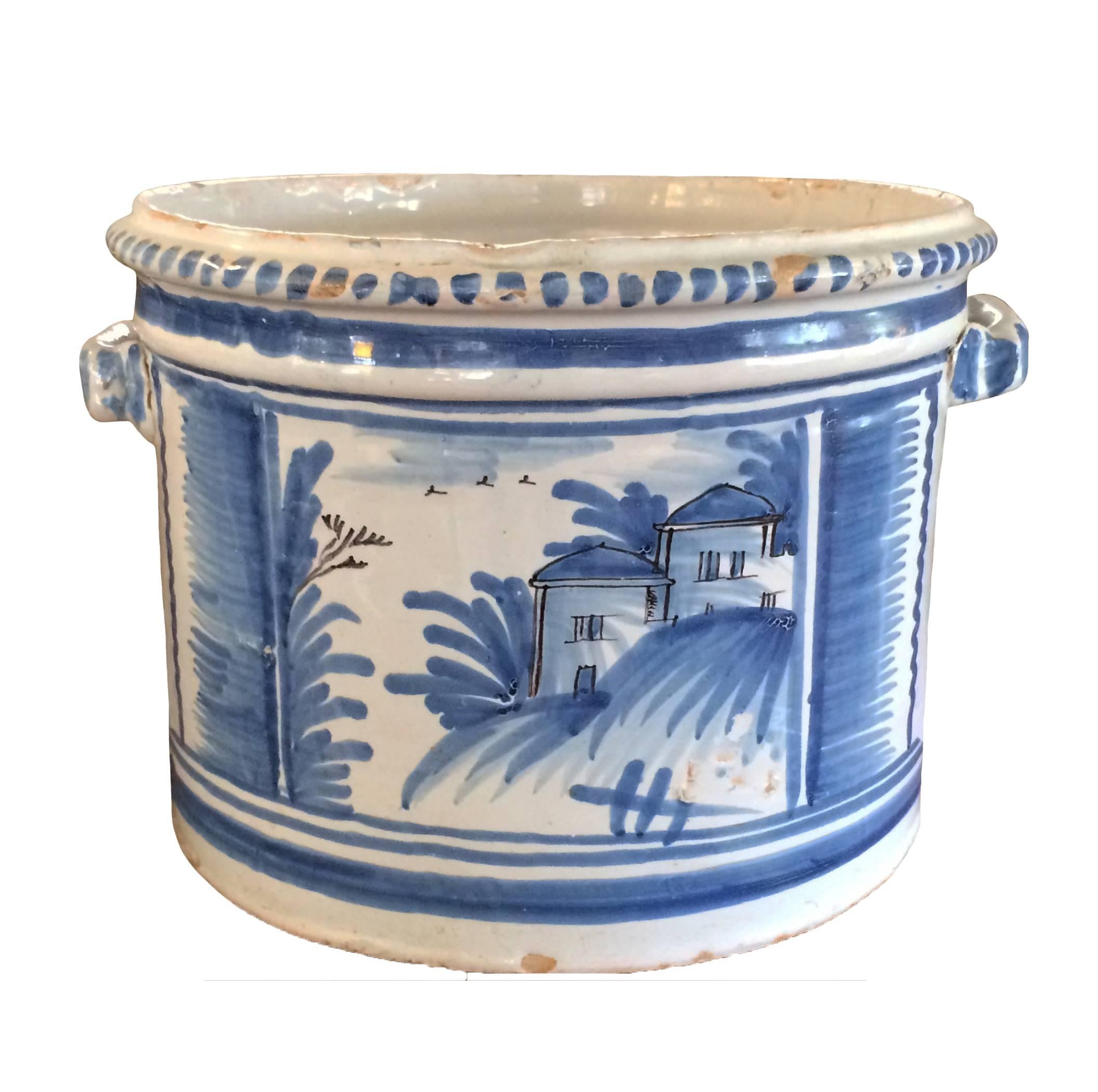 Delft blue and white jardinière with handles; varying landscape scenery depicted on each side; tulip decorated side panels; 18th century.
