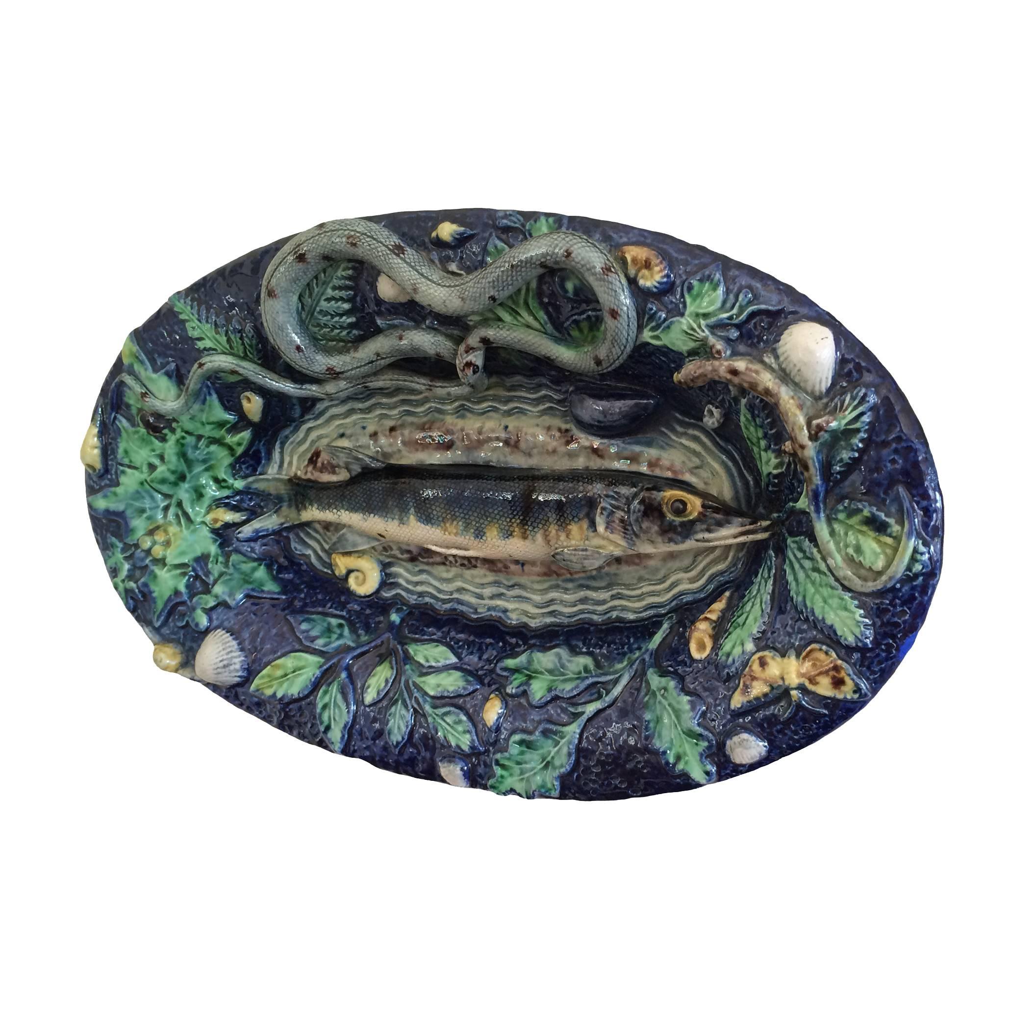 French Majolica Pallissy Trompe L'oeil hand-painted platter; depicting fish surrounded by snakes, butterflies, shells and vines, 19th century.
 