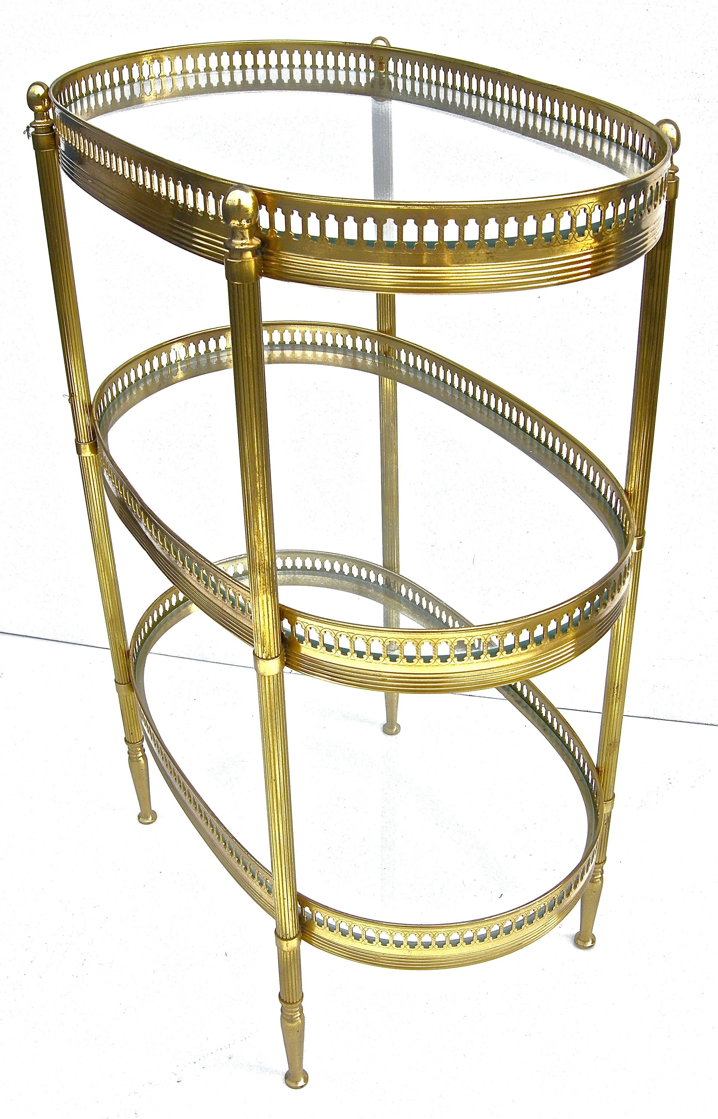 Elegant, vintage French, brass and glass, diminutive three-tier side table in the Jansen manner and taste. Highly detailed with cut out accent surround shelves with classic fluted, column-style legs on ball accented feet. Warm aged surface and