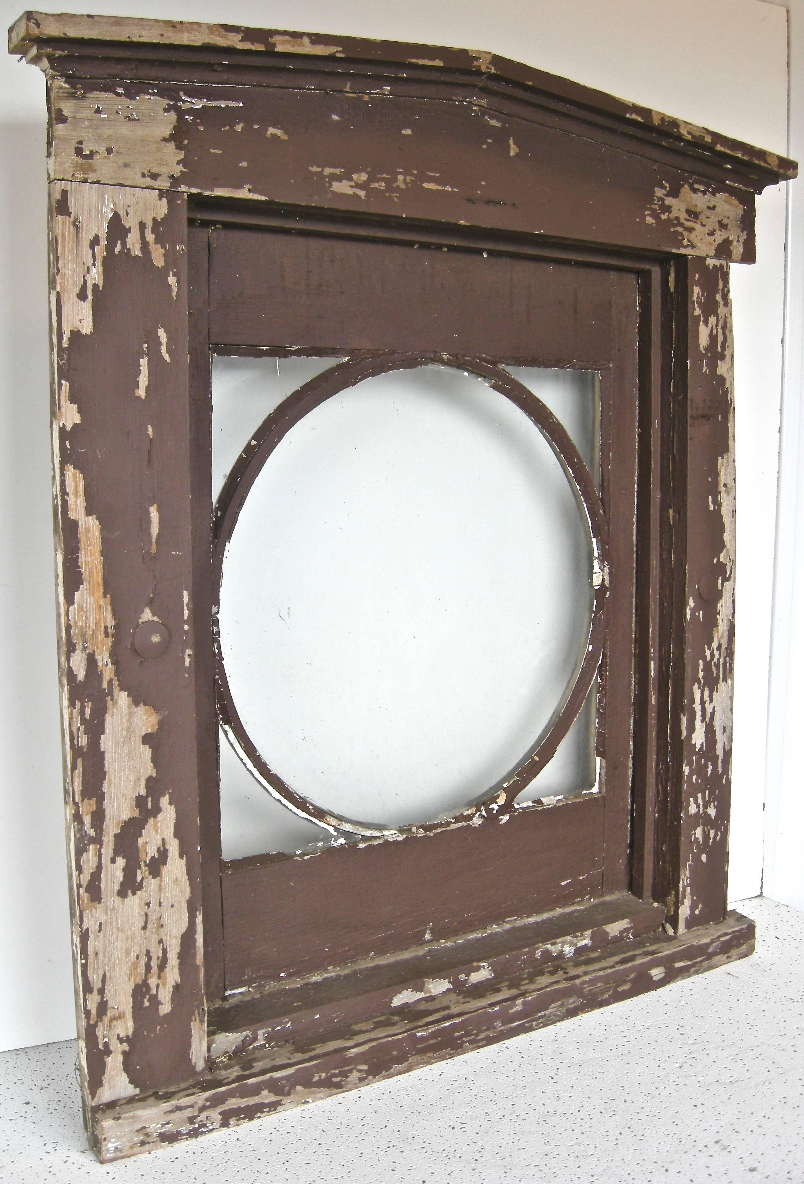 Terrific, early, classically-inspired window frame. Handcrafted having a circular focal point encased in a rectangular frame with a raised pediment top. Original glass. Early brown paint in distressed, worn and weathered overall finish. Southern