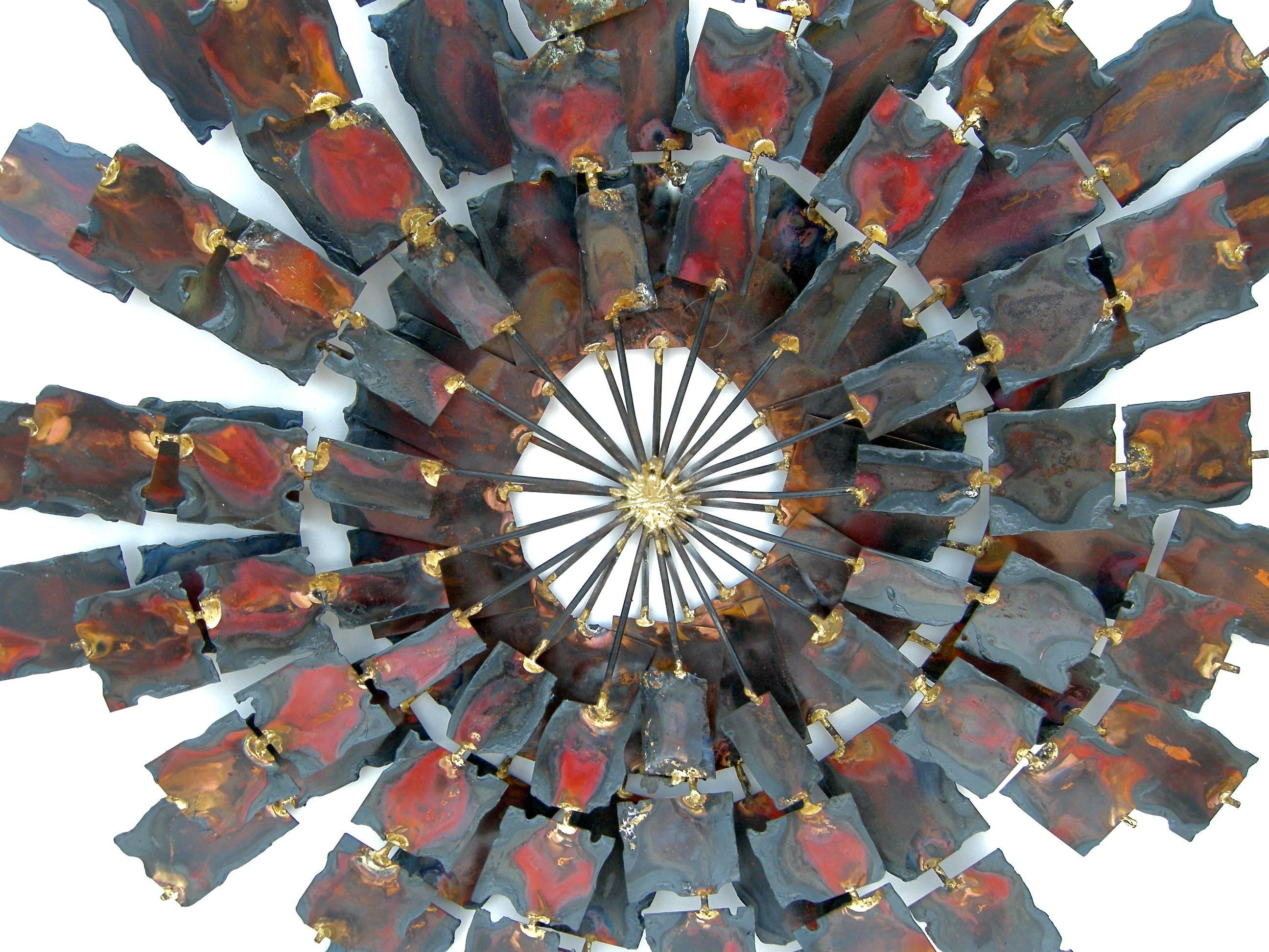 A striking, vintage, mixed metal starburst wall sculpture. Graphic, hand-cut, radiating metallic arms in varying shades of color and patina. Attributed to designer William Bowie.