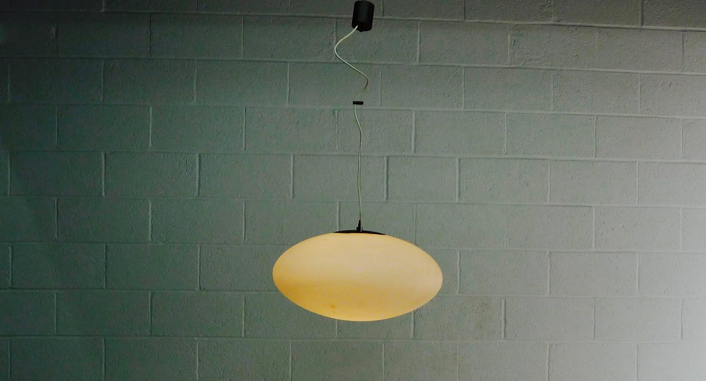 Stilnovo, Italy, 1960s. Opaque glass pendant light with mechanism allowing it to be hung off horizontal as shown in image 4. 
Interior retains original yellow label.