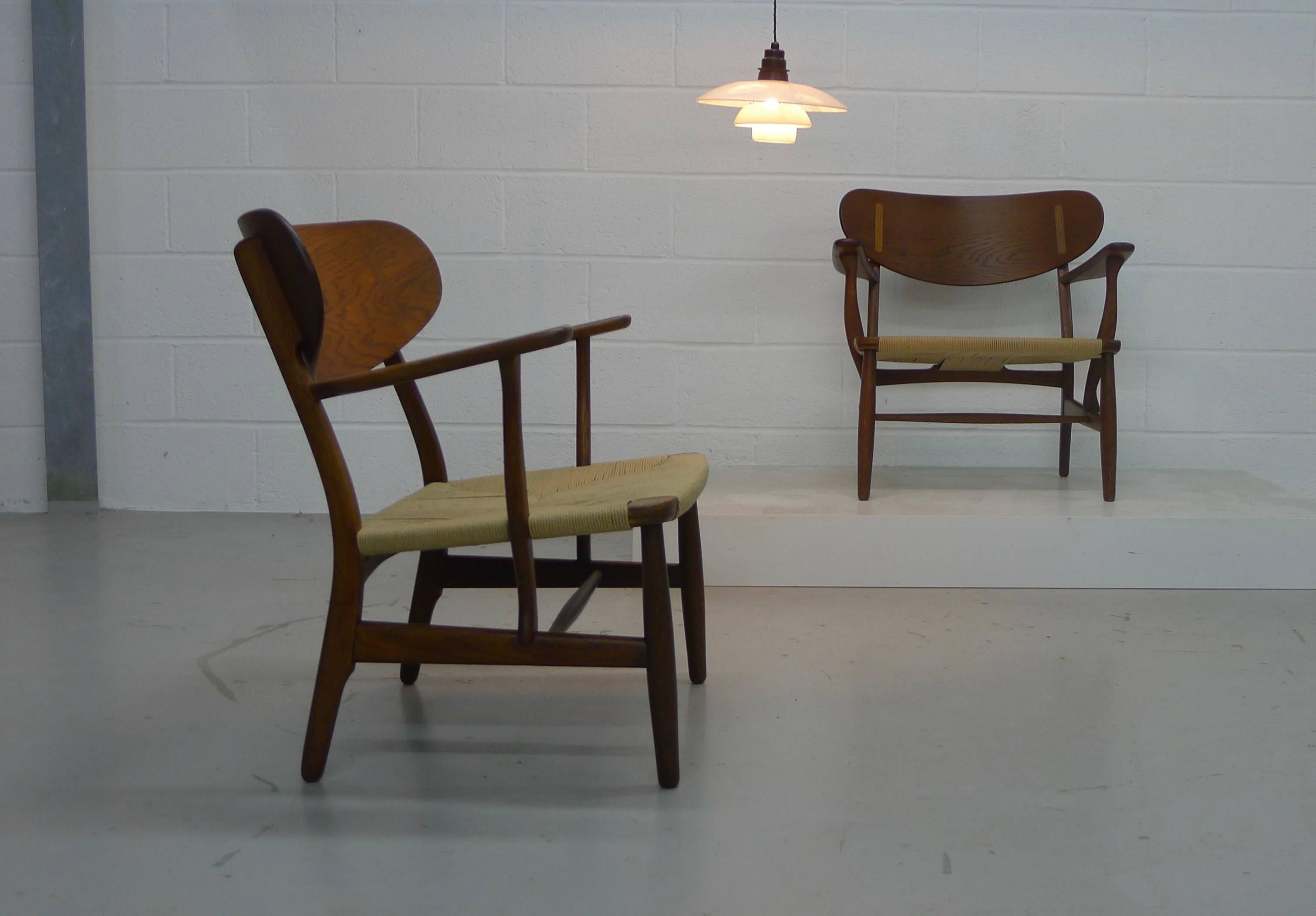 Hans Wegner, Denmark, designed 1951, a pair of CH22 armchairs of oak and paper cording. In fine vintage condition with renewed seat cords, makers mark stamped to underside of arm on both examples and one with the Danish Control tag under the other