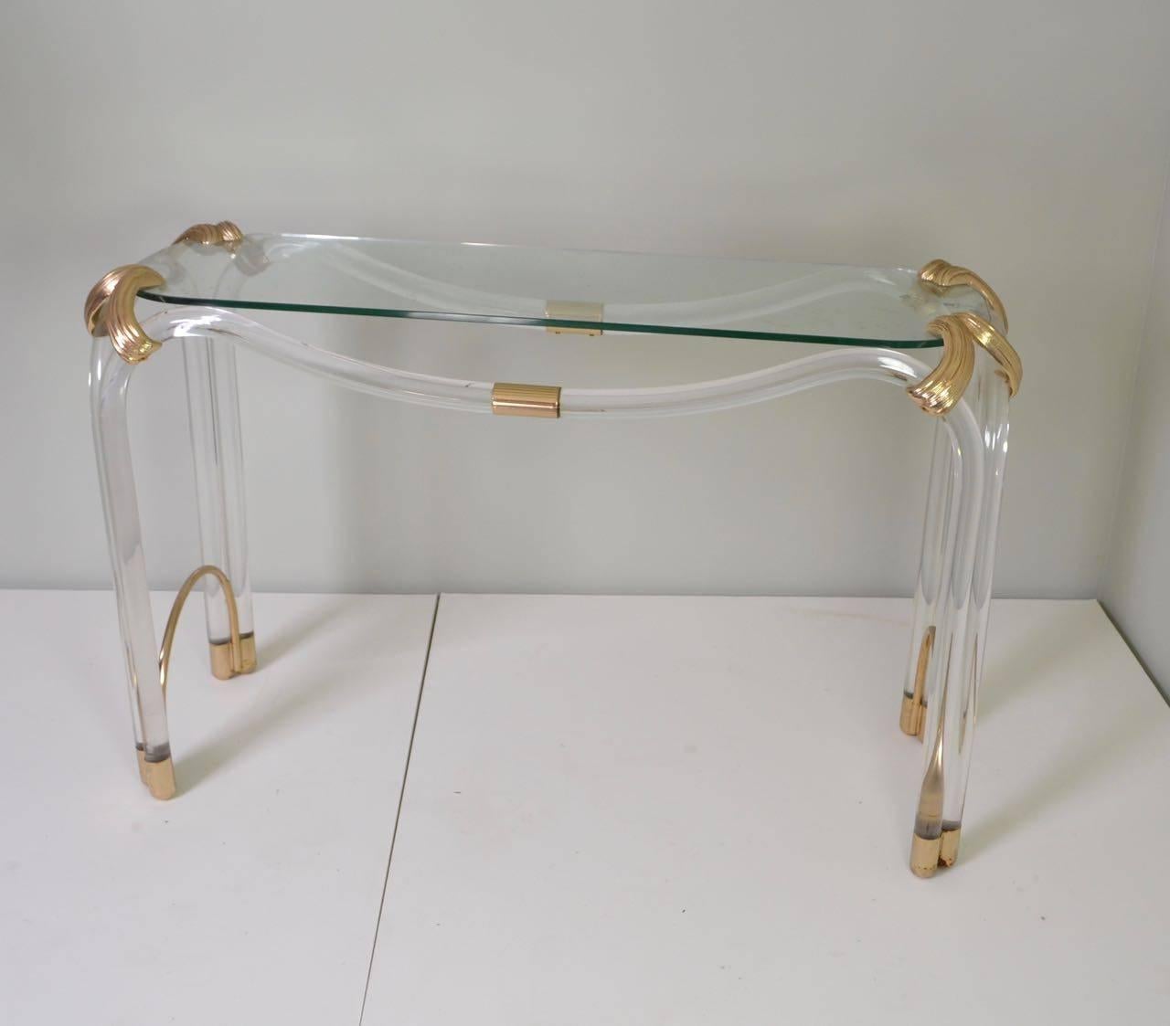 Freestanding perspex console with lacquered brass mounts and a glass top.
 