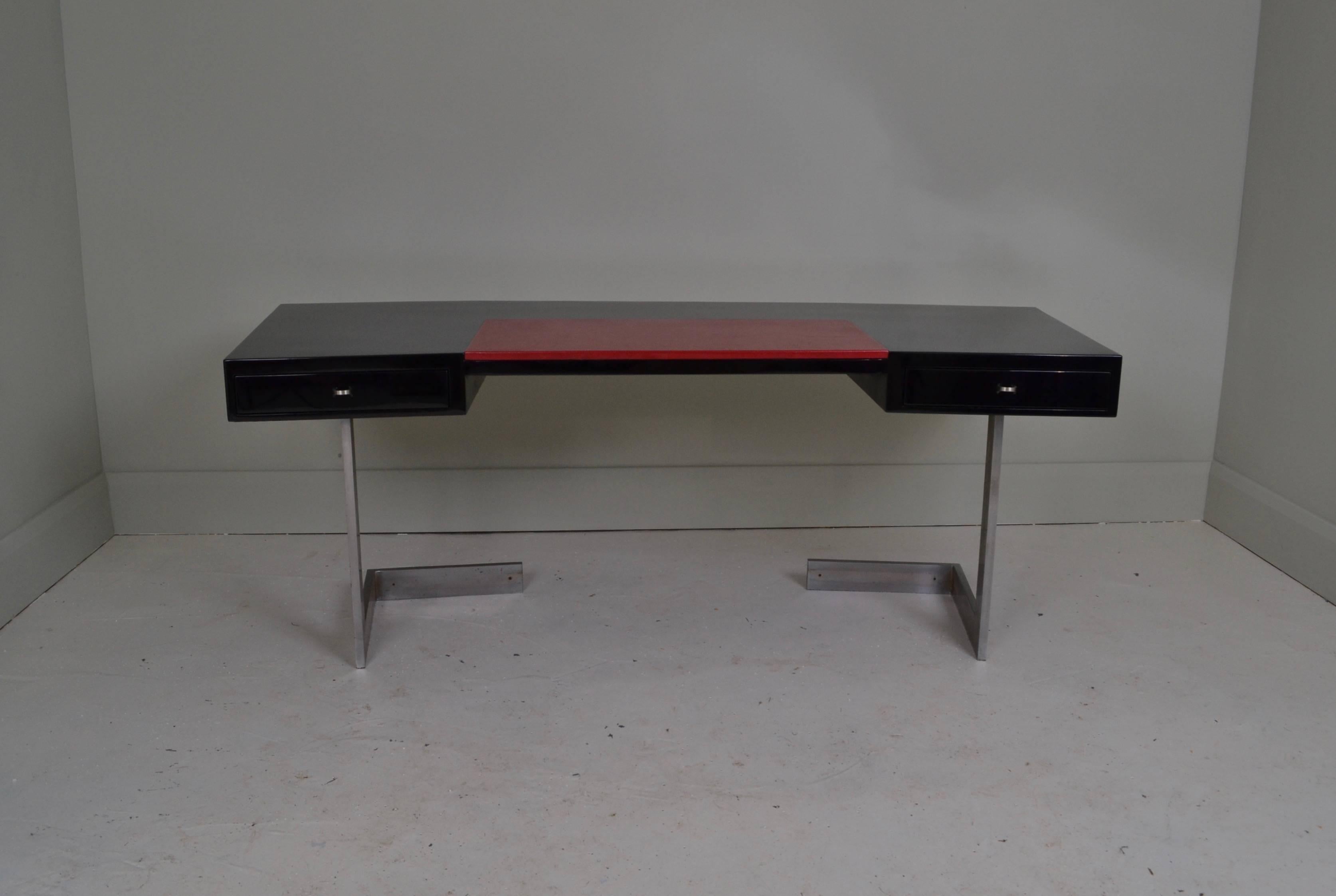 Black lacquered two-drawer desk of curved form with
original red leather insert and chromed steel legs.