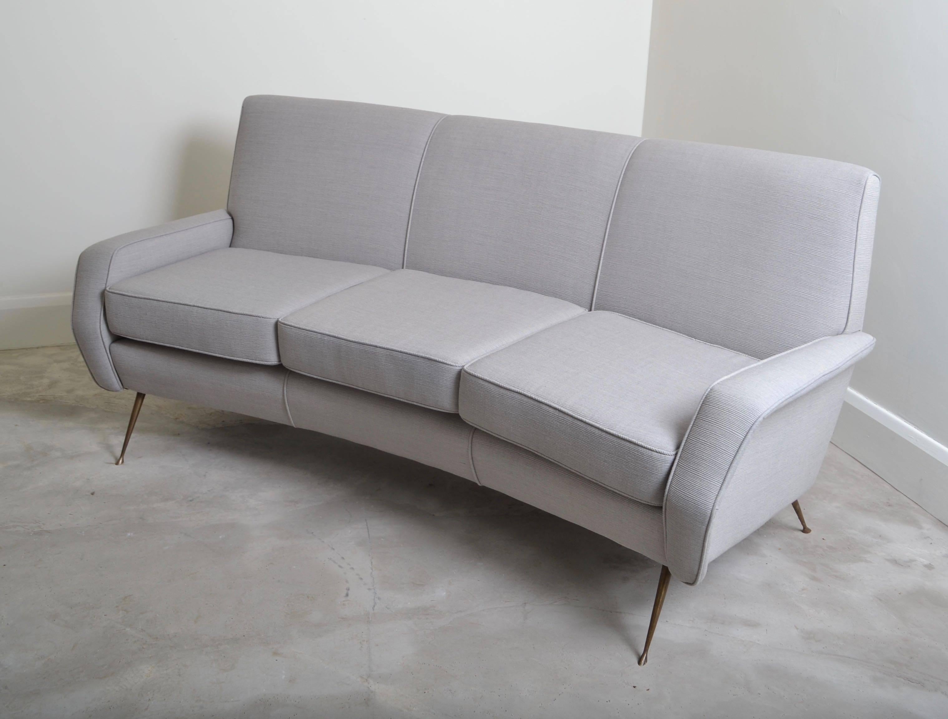 Three seater curved sofa designed by Gigi Radice , Italy 1950.
The sofa has been completely renovated and re-upholstered in a
Kvadrat grey fabric with a slight ribbed texture.
The legs are lacquered brass and add a nice sculptural element 
