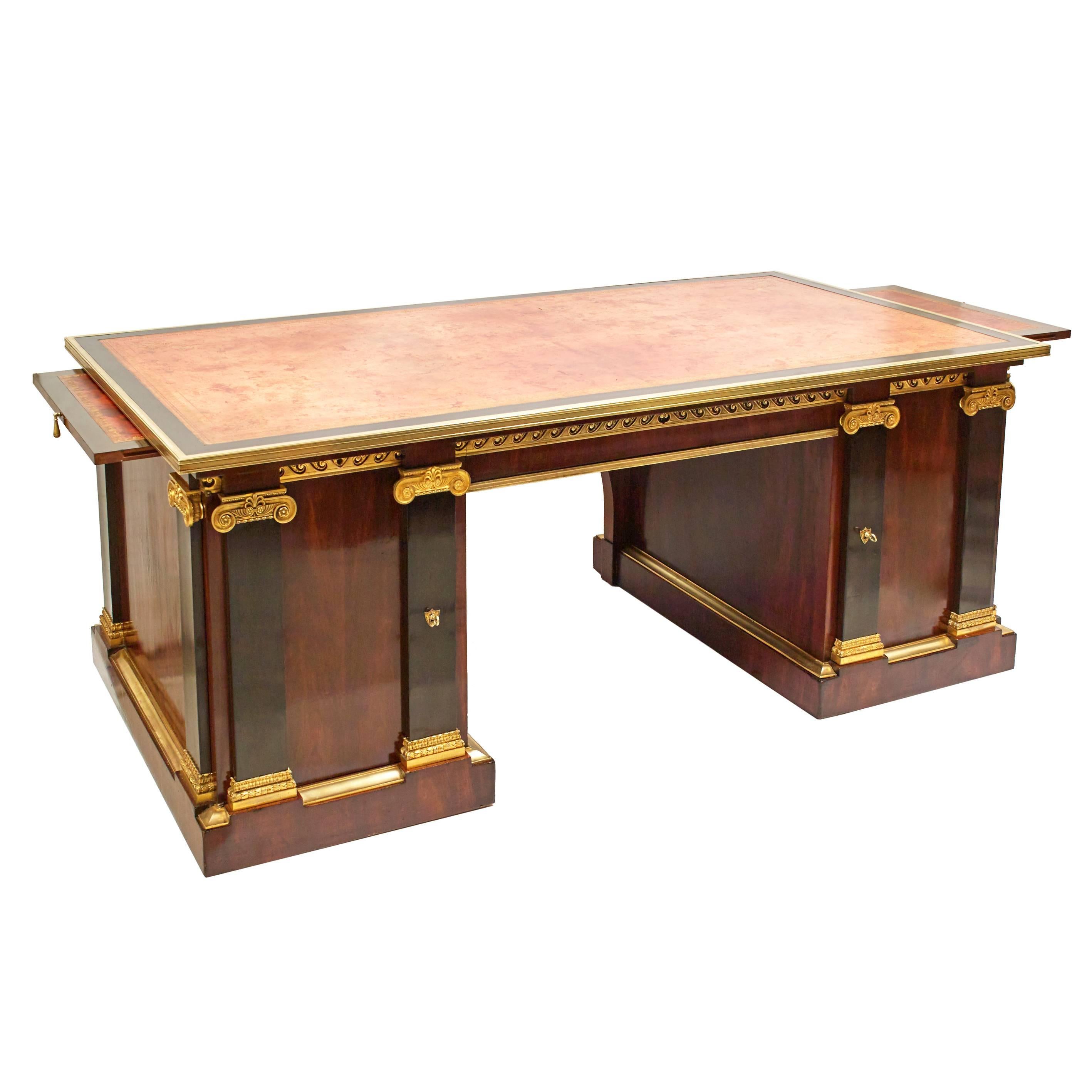 An impressive French Empire neoclassical pedestal desk in mahogany with ebony details, circa 1850. Mounted in ormolu, with ionic column and Vitruvian scroll decoration, and extension leaves measuring 31cm each. Boasting an original leather top