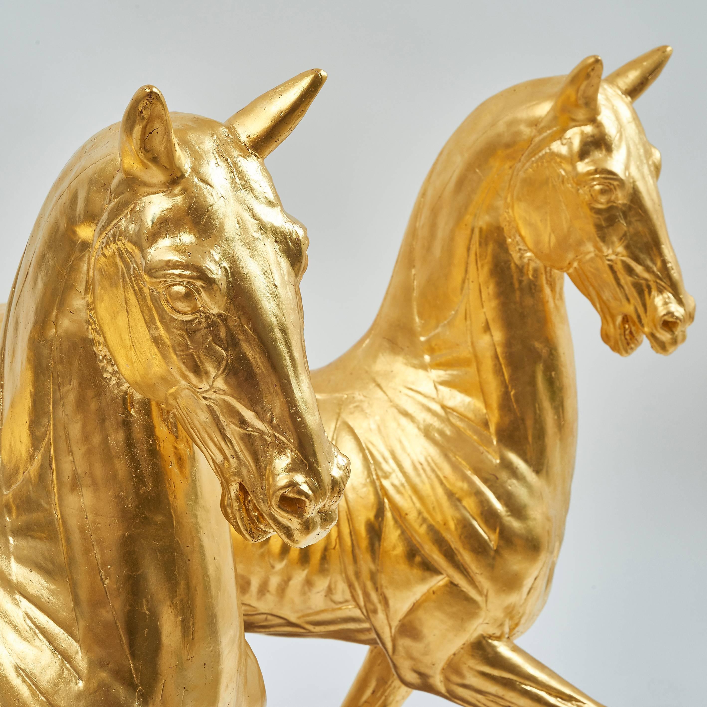 A pair of late 19th-early 20th century full scale gilded plaster pacing horses, representing the bronze flayed pacing horse sculpture by Giambologna, first created at the end of the 16th century and thought to have been influenced by some of