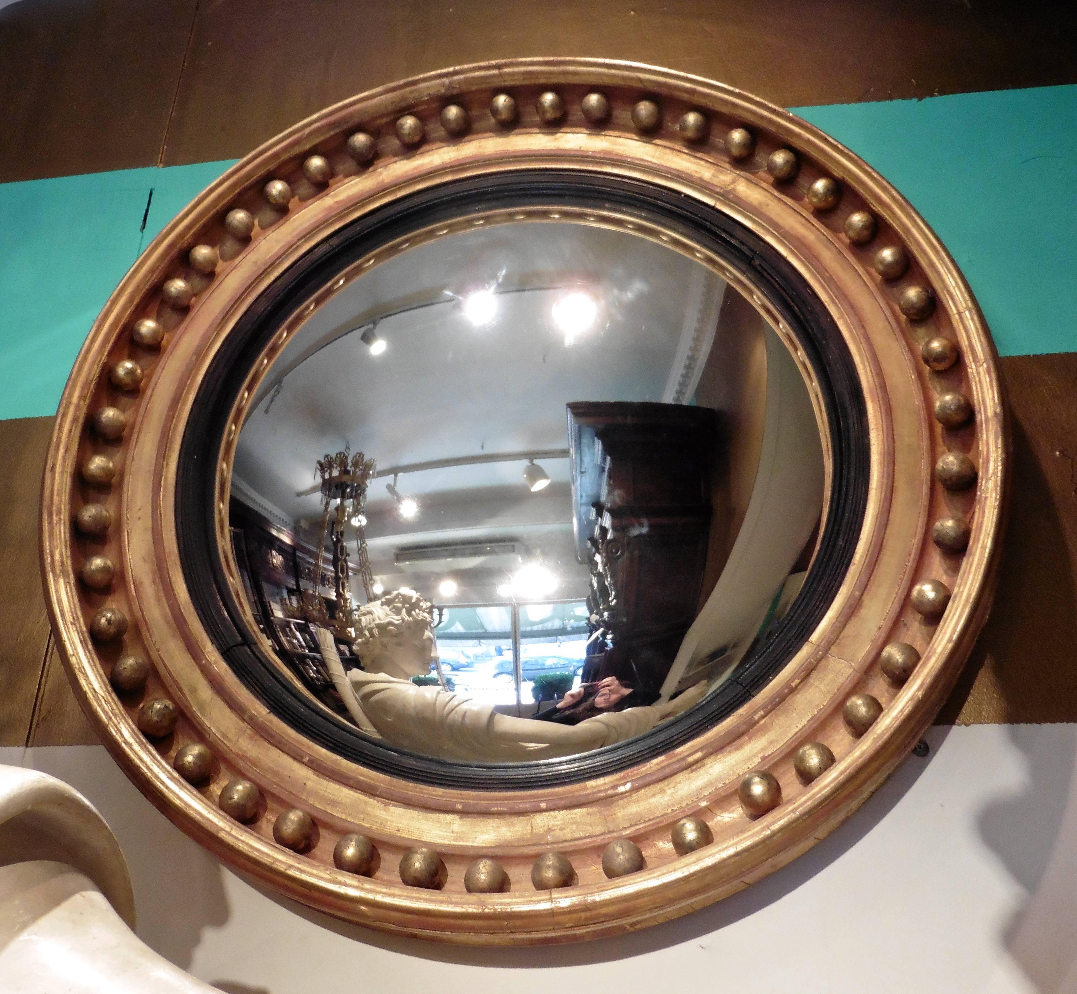 A fine English Regency large giltwood framed convex mirror, circa 1820. With gilt spheres and a reeded ebonized slip.
 

 