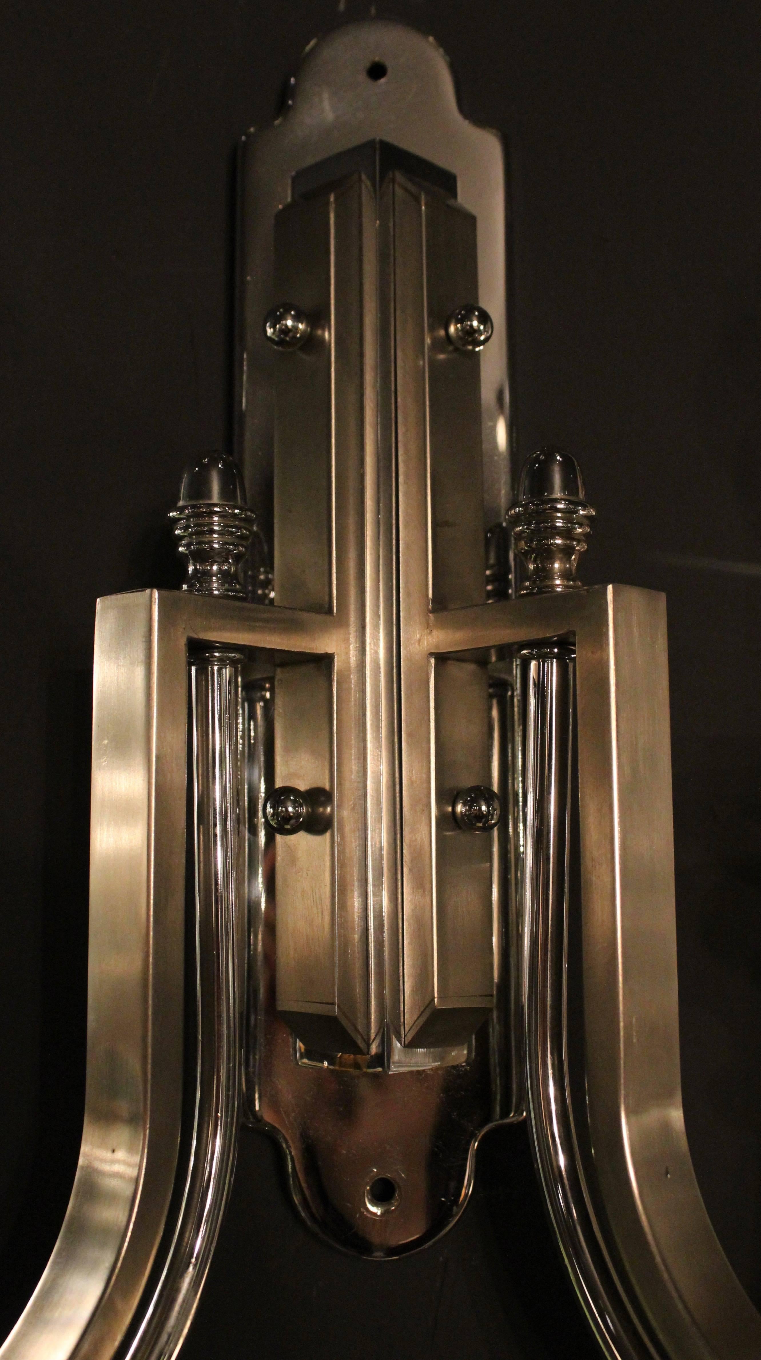 Pair of Art Deco revival wall sconces, circa 1960. In chrome, Minimalist in design, with two curved arms emanating from a shaped backplate. Each arm terminating in a circular drip tray and simple chrome candles. Wired for the UK.
 
 


 