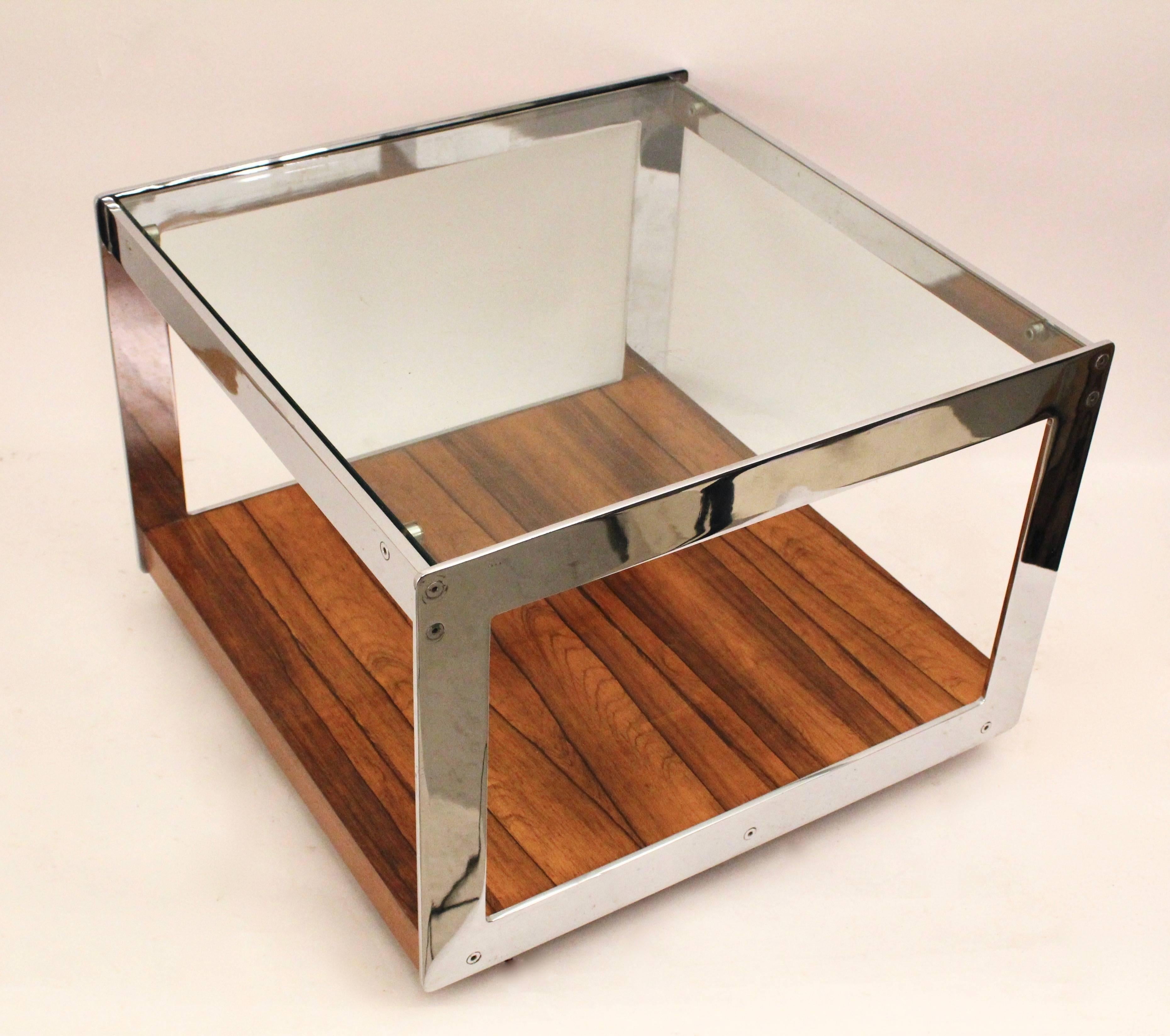 A pair of square chrome coffee tables by Merrow Associates, with a simple sledge style base, circa 1970. The top consisting of a clear glass panel, supported by a chrome frame, with the bases in a contrasting rosewood. Each table on its original