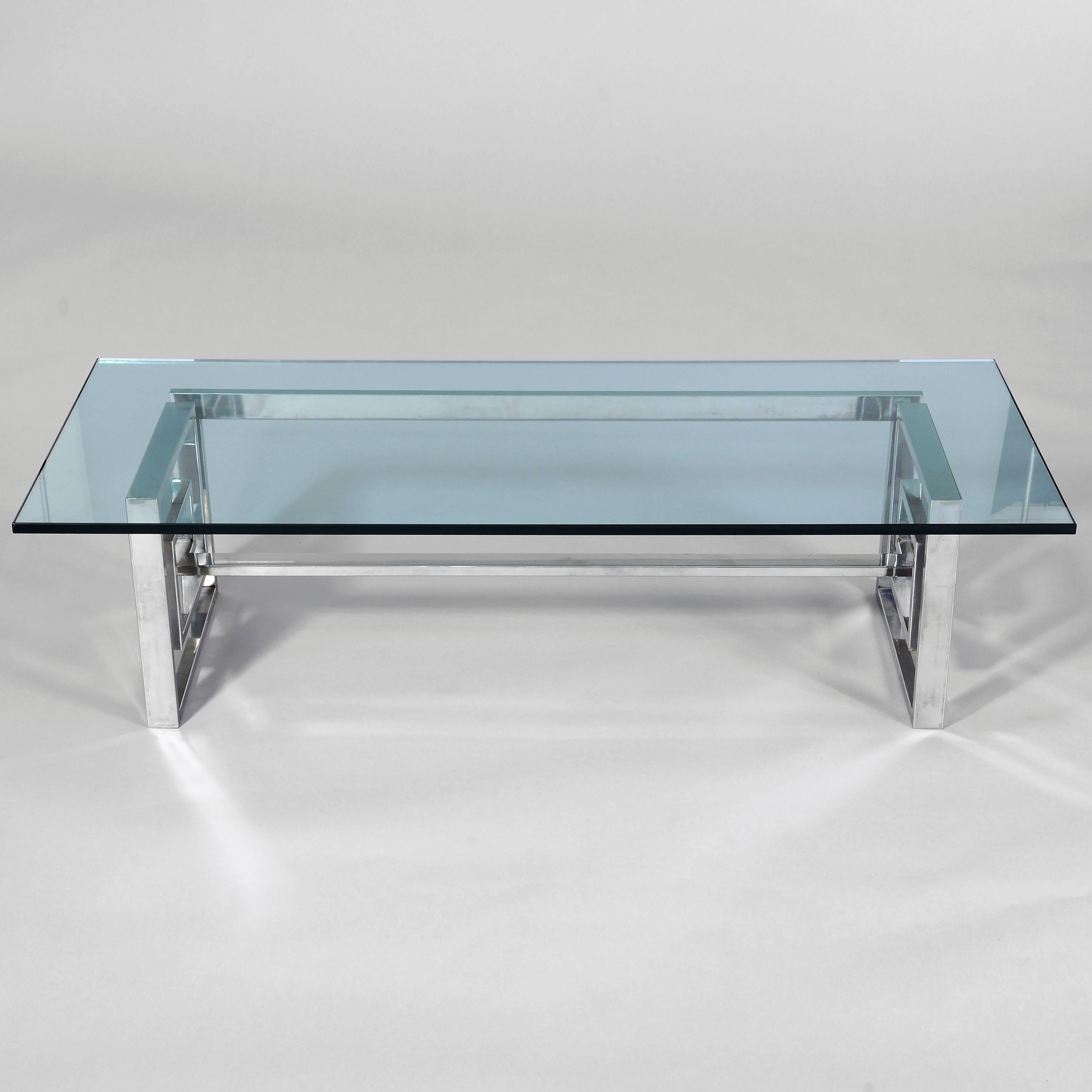 Ein glamouröser Tisch aus Stahl und Glas. Der Stahlsockel, der zu einem durchgehenden Band geformt ist, trägt eine klobige, massive 20 mm (ca. 3/4 Zoll) Glasplatte. Der Sockel ist mit der Marke 