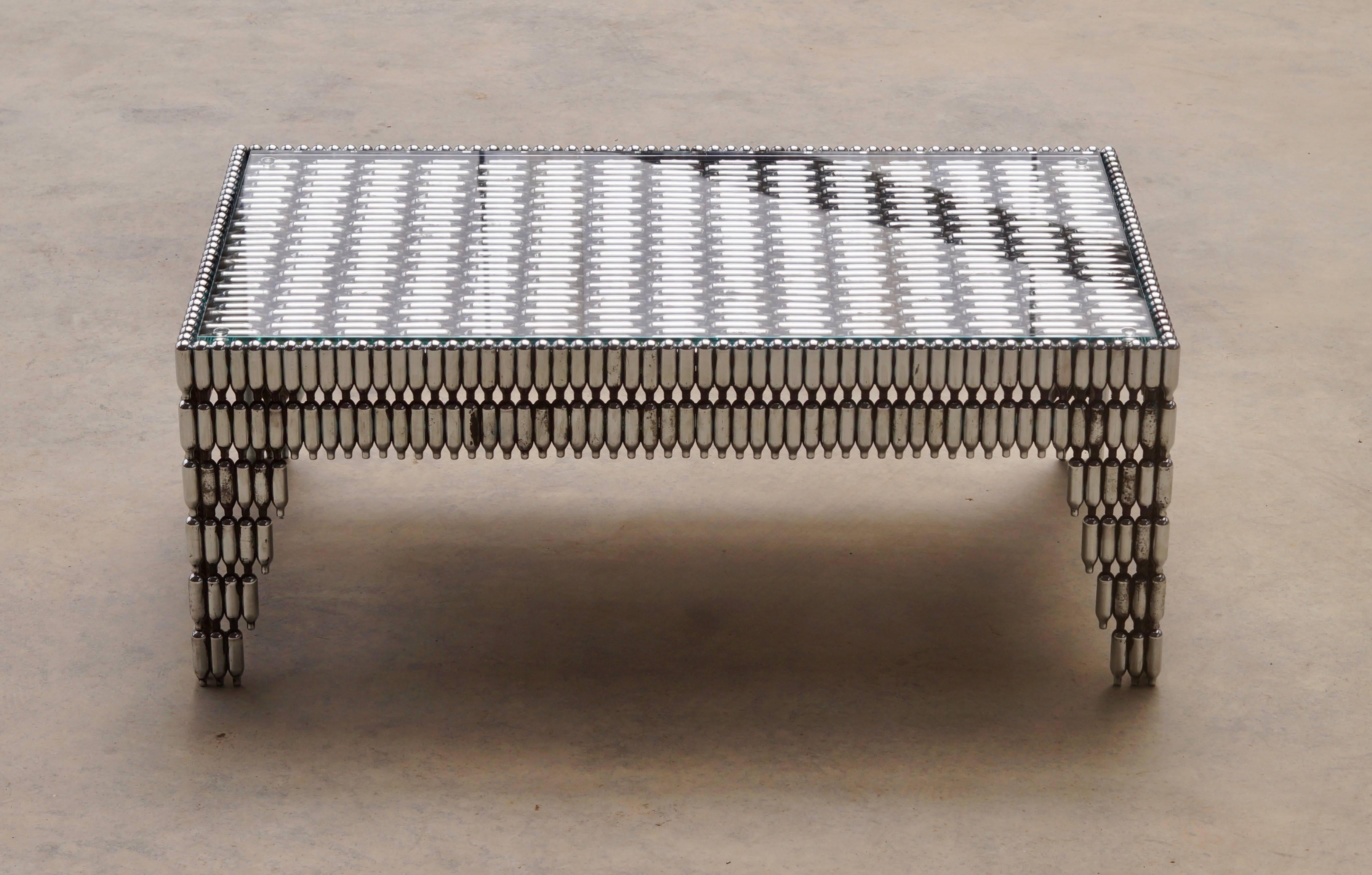 This unique sculptural coffee table is made from used NOS or laughing gas canisters which were commonly found littering the ground after music festivals and parties. These canisters were originally intended for making whipped cream in restaurants