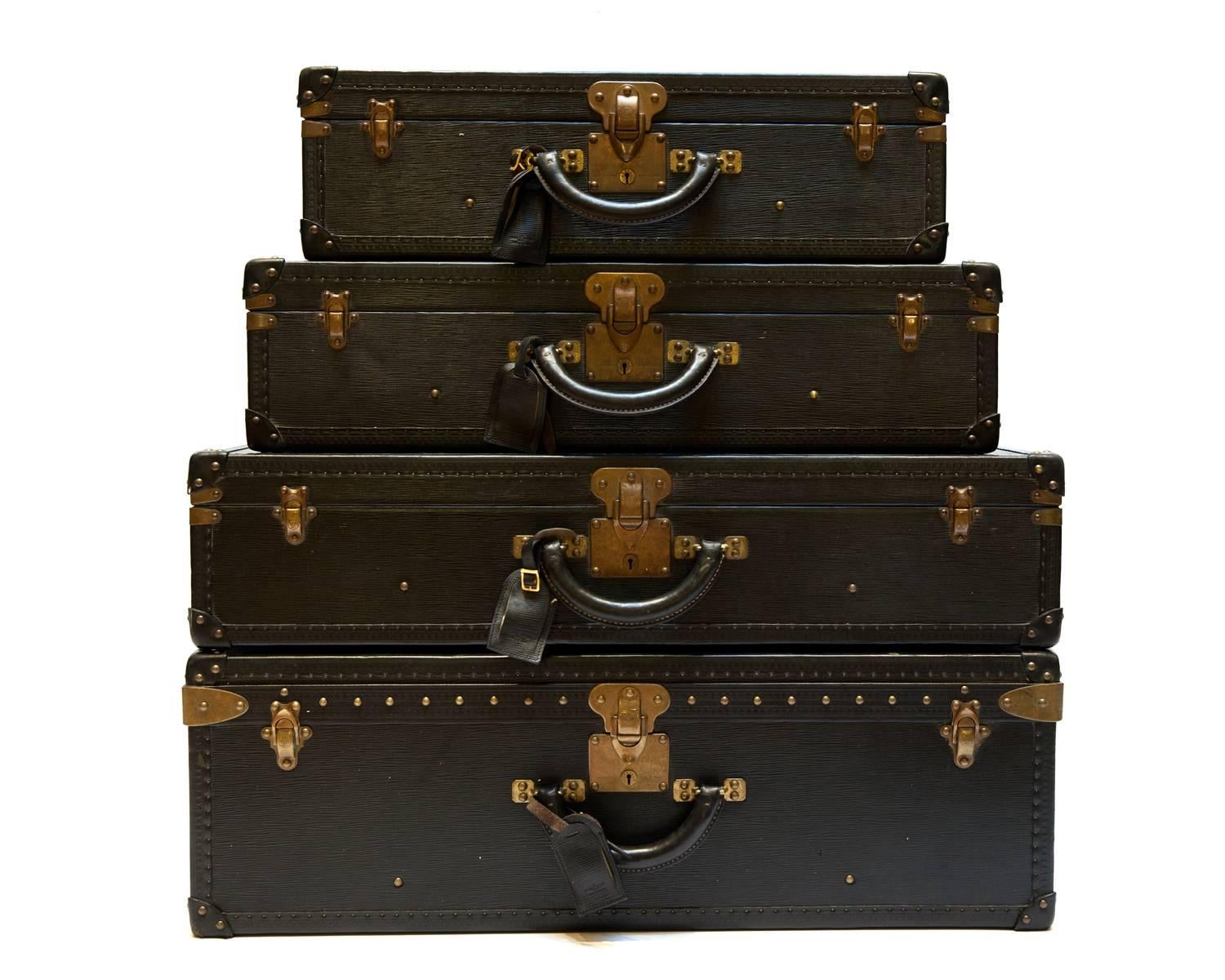 A rare set of four matching black Epi leather hard-sided luggage. 
These come from the original owner, purchased in the mid-1980s. They were never used and remained stored until now. The pieces are all numbered consecutively and come with two