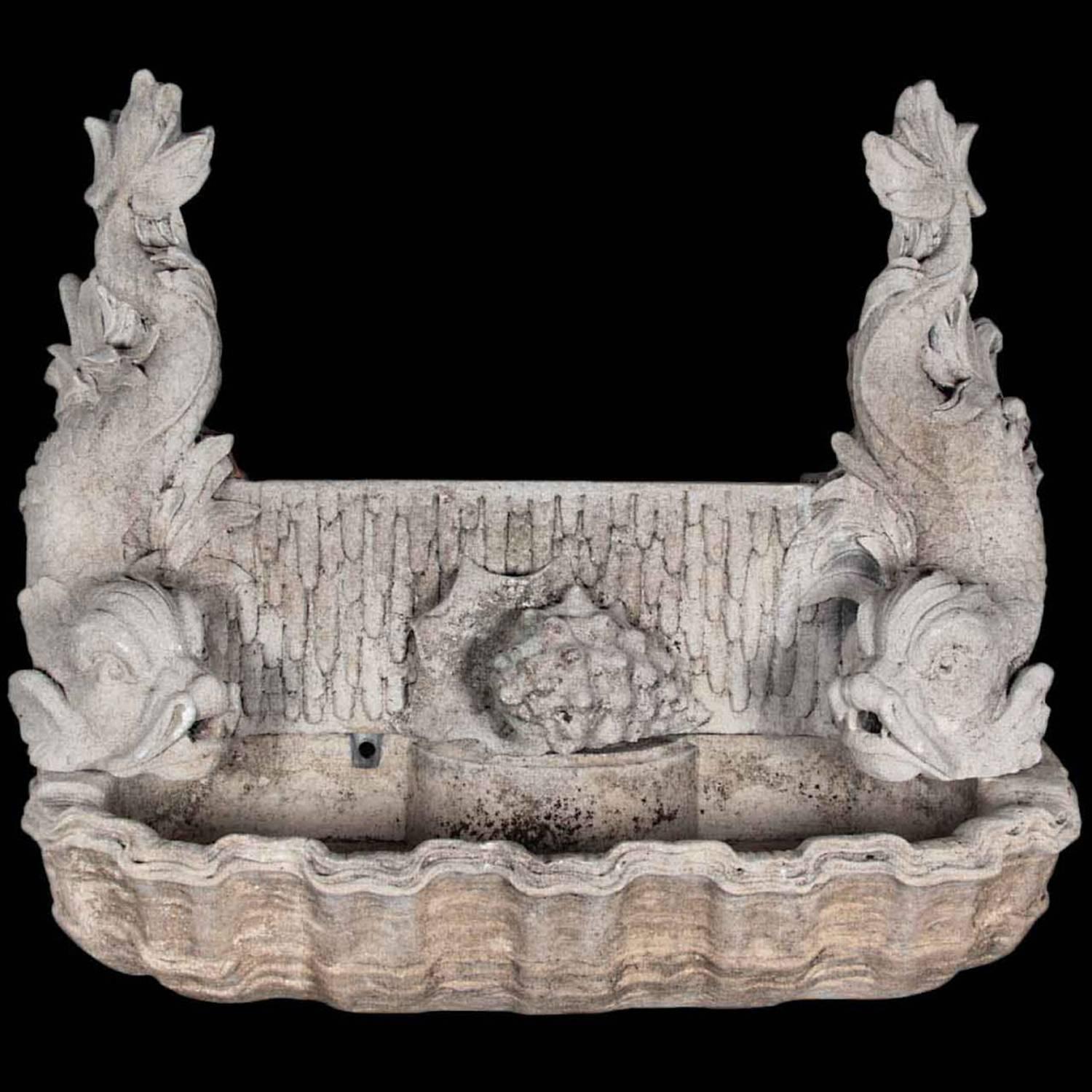Italian, turn of the century, hand carved limestone fountain. A pair of exceptionally carved dolphins flanking a conch shell sit atop a stylized shell basin. Two water feeds are already in place terminating at the mouth of each dolphin and the water