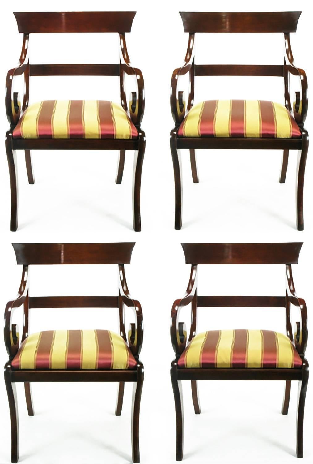 Striking set of four dining armchairs, crafted in mahogany, displaying scrolled arms and klismos style legs. Upholstered in vintage berry red and gold stripe silk.