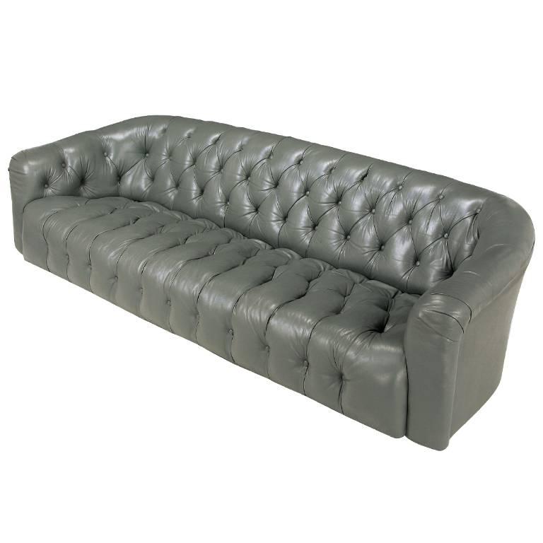 Elegant sloped shoulder sofa from Baker. Original slate grey button tufted seat, back and arms, and still in wonderful condition. Comes with the original brass casters. If desired, casters can be replaced with wood legs as an option. Attributed to