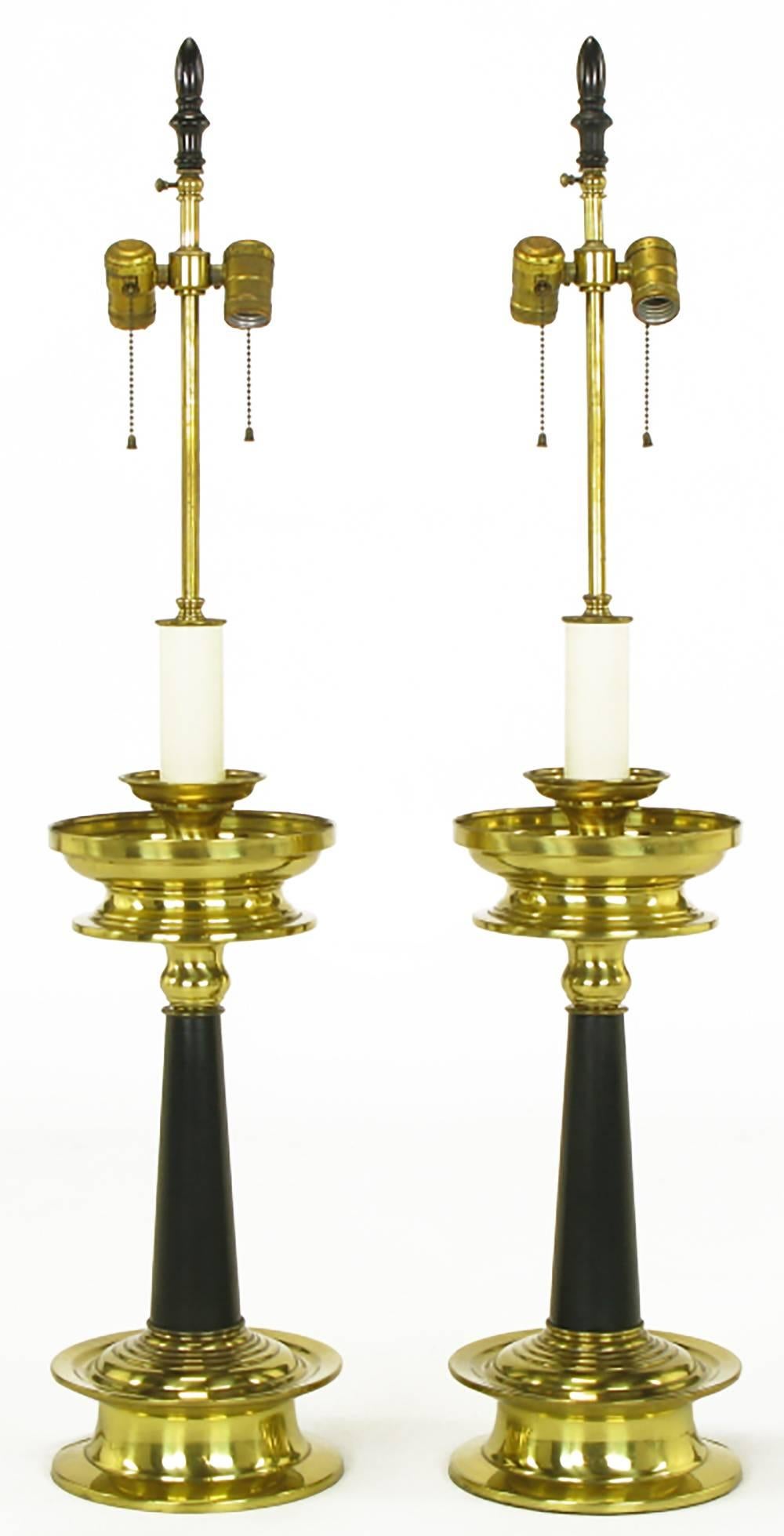 Pair of substantial brass and black lacquer table lamps with double top bobeches. Double socket cluster atop a brass stem and off-white candle style spacer. Similar in style and substance to lamps by Stiffel and Marbro.