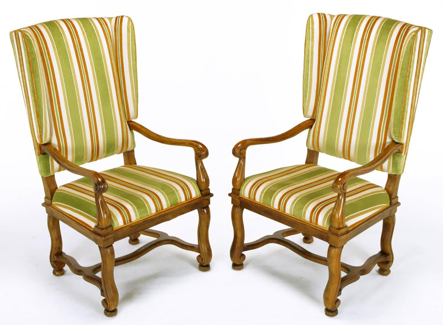Pair of Heritage Furniture, Louis XIV inspired, winged fauteuils. Carved and patinated walnut frames with curved arms and legs with H stretchers. Original cut velvet upholstery striped in olive green, umber and taupe.

Measures: Arm height 25