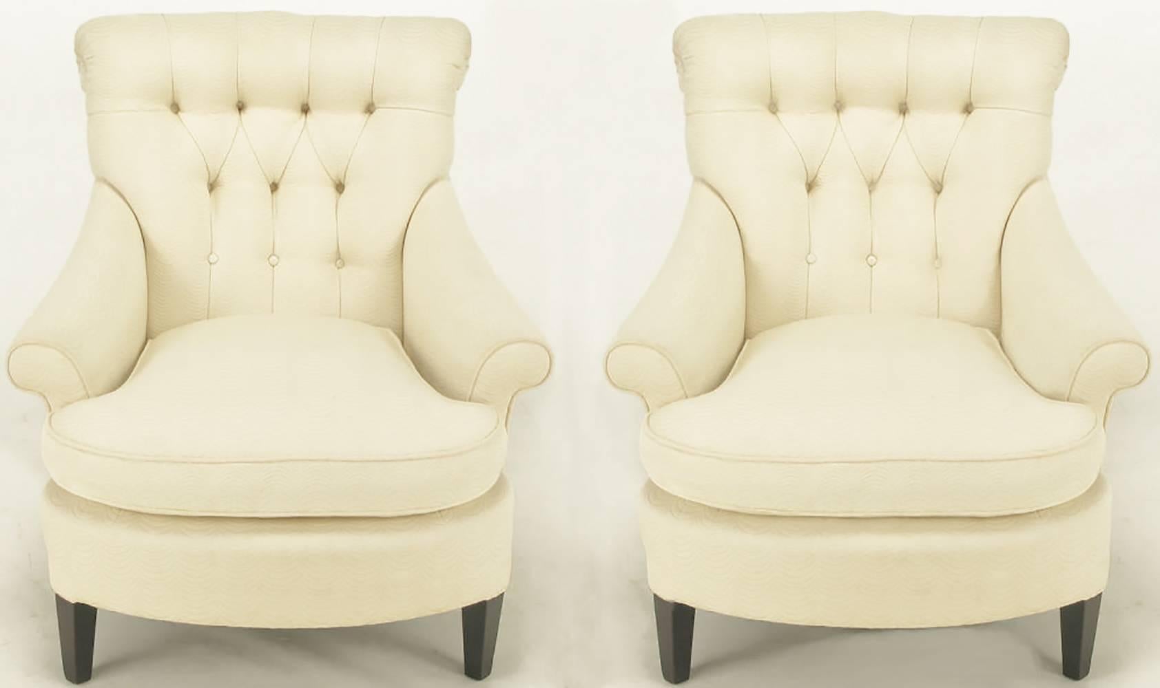 Pair of ivory cotton/silk blend upholstered button tufted lounge chairs with rolled arms with rolled large button detailed backs. Loose down filled seat cushions, canted walnut front legs with raked back legs and curved front. Upholstery is woven