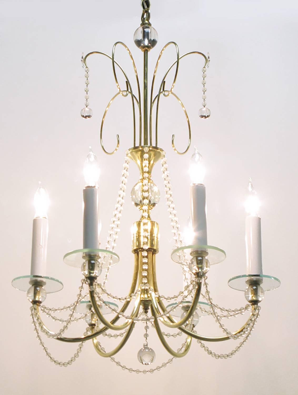 Lustre à six branches en boule de cristal de roche et laiton avec des bobeches en verre et une chaîne en cristal perlé. La tige centrale est ornée d'une boule de cristal supérieure et de quatre gerbes en laiton filigrané. Jusqu'à 360 watts de