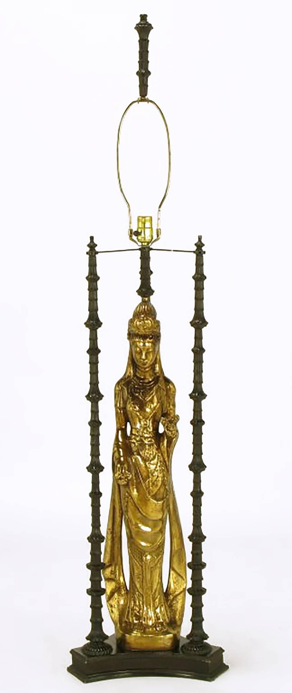 In the manner of James Mont or Tony Duquette, this 55 inch tall lamp contains a doré bronze statue of Quan Yin a/k/a Kuan Yin a/k/a Guanyin, the Chinese goddess of mercy. Lacquered metal three-column shrine surrounds her. This Asian form table lamp