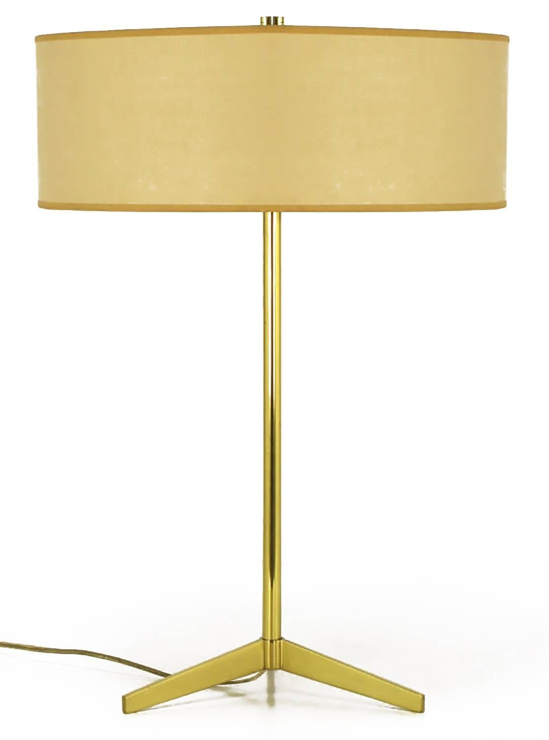 Simple and elegant brass tripod based table lamp by Lightolier. White porcelain dual sockets with white metal disc housing. Sold with drum shade and pierced top diffuser. From the period when Lightolier imported lamps by Arteluce, although we have