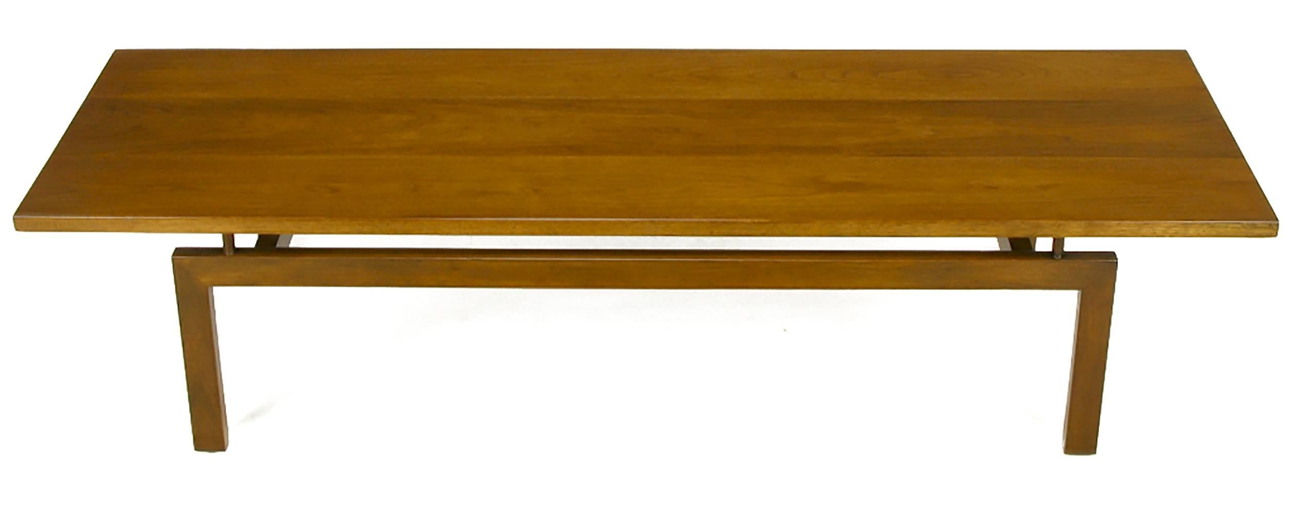 Floating top walnut coffee table after designs by Paul Laszlo for Brown Saltman. Solid three piece top is surmounted atop four wood cylinders. U-shaped walnut legs with a pair of inconspicuous recessed stretchers.