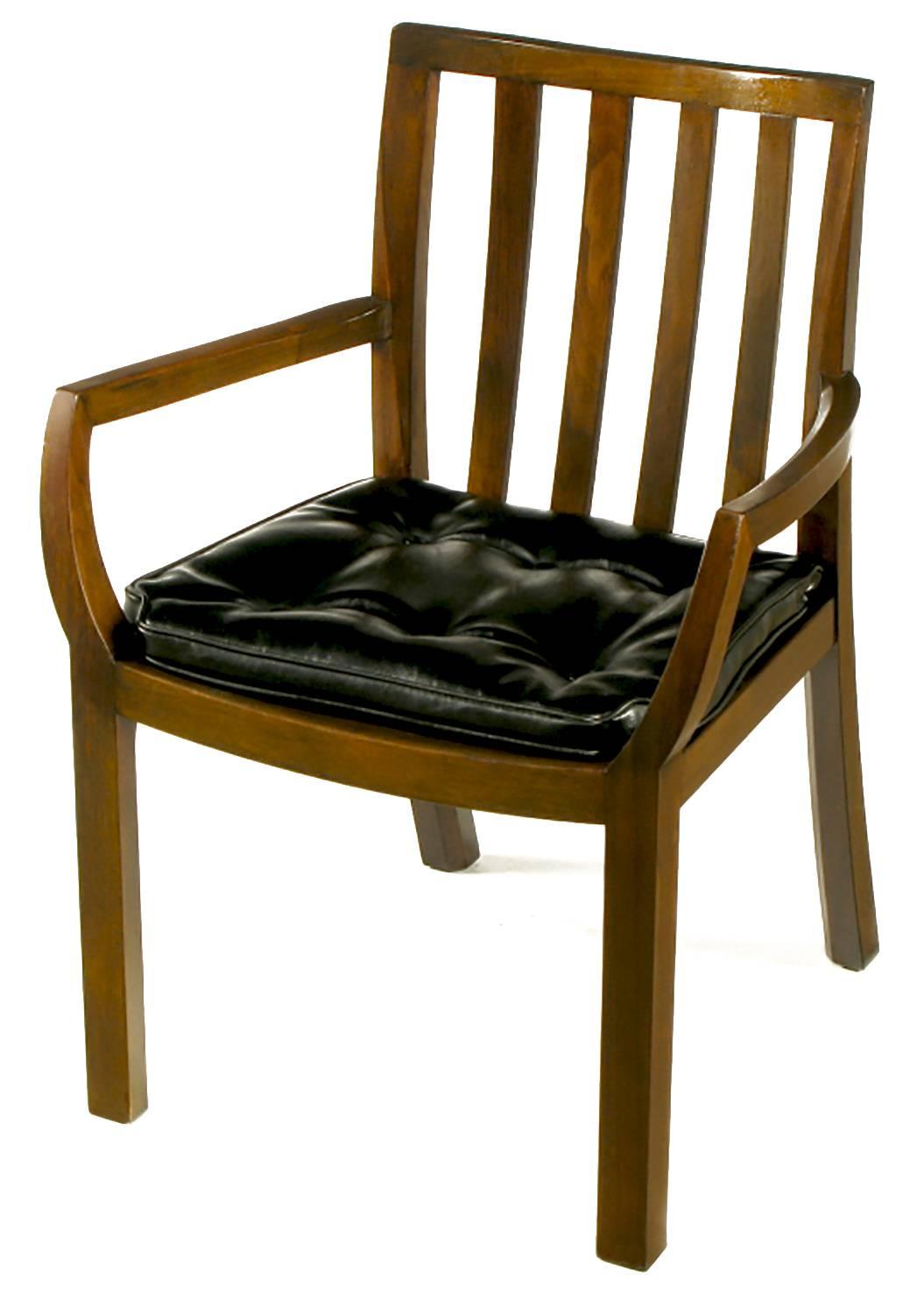 From Bert England's Forward Trend collection for Johnson Furniture of Grand Rapids, these elegant chairs are constructed of solid walnut frames, with button tufted black leather seats. Modest barrel backs and boat rib like arms to the armchairs.