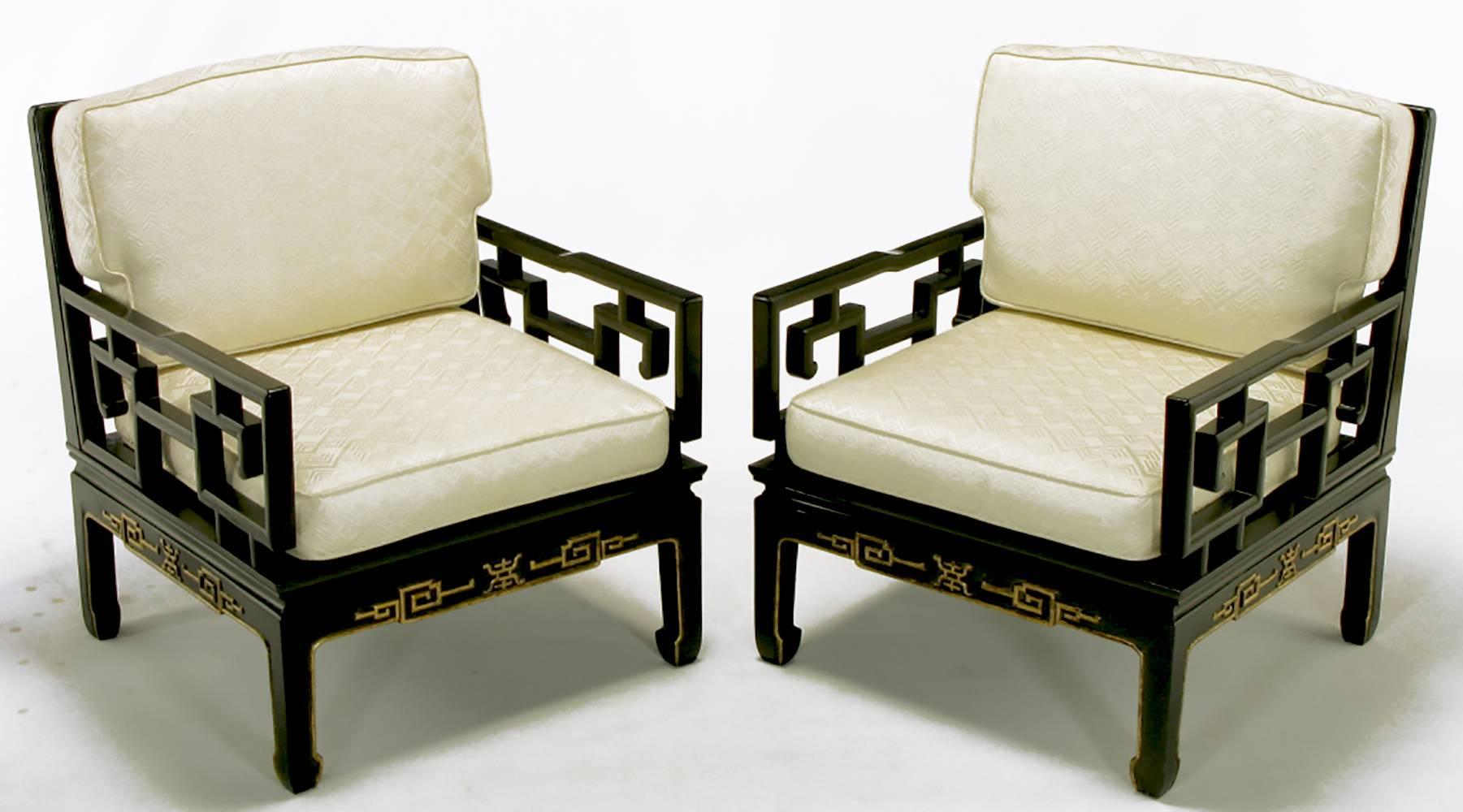 Very fine pair of Chinese design club chairs with hand-carved natural mahogany and gilt detailing. These club chairs look equally stunning with or without the geometric design ivory silk upholstered backs.