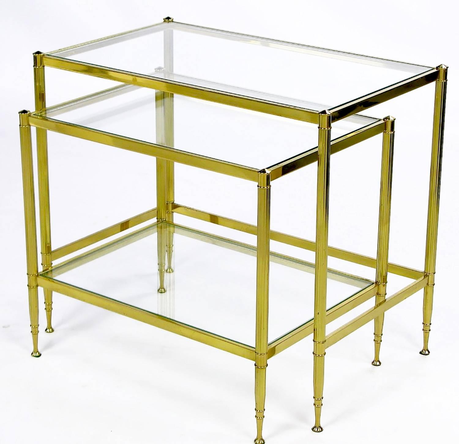 Polished brass nesting tables with double ferrule detailing that begins at the top of each leg and continues to the beautifully shaped feet. The smaller nested table has both a glass top and lower glass shelf.
Smaller table: 18.50