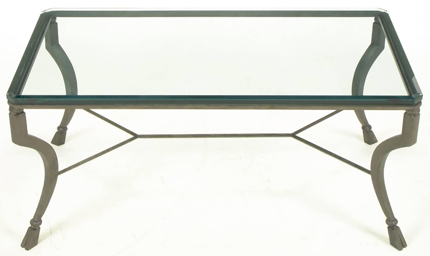Antiqued metal hand-wrought and welded iron coffee table with canted legs and hoofed feet with iron ball spacers. Double Y stretcher support and beveled glass top with canted corners.