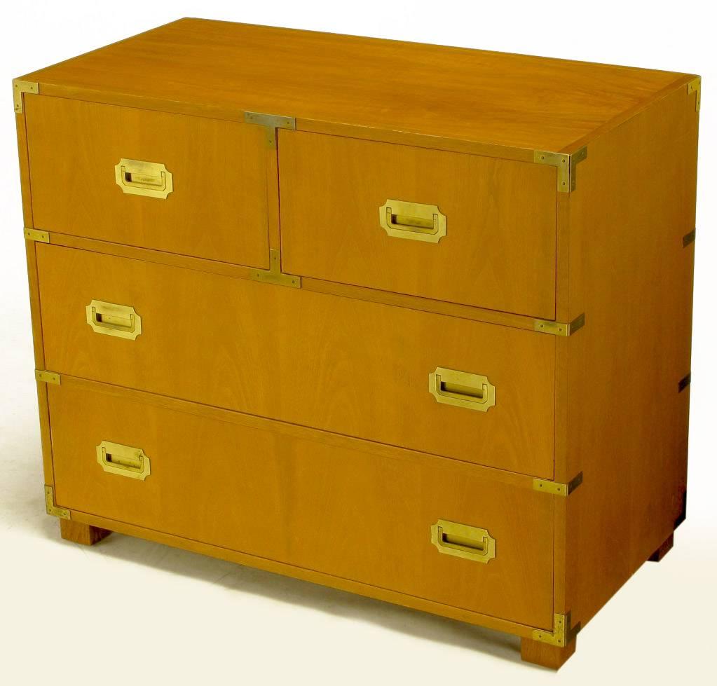 Baker bleached walnut four-drawer Campaign style commode. Brass corner guard detailing and brass flush drop bail pulls. Recessed square block feet. Finished on all four sides.